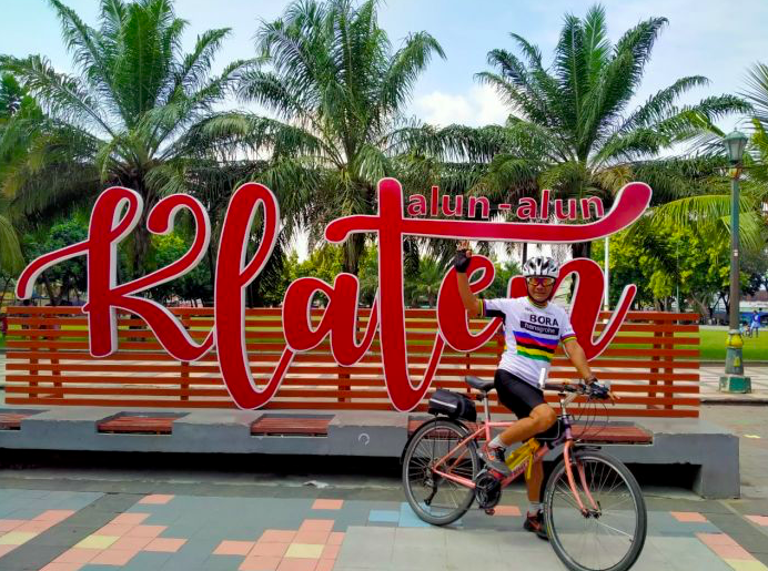 Seorang pesepeda berpose di depan papan nama Alun-Alun Klaten.
