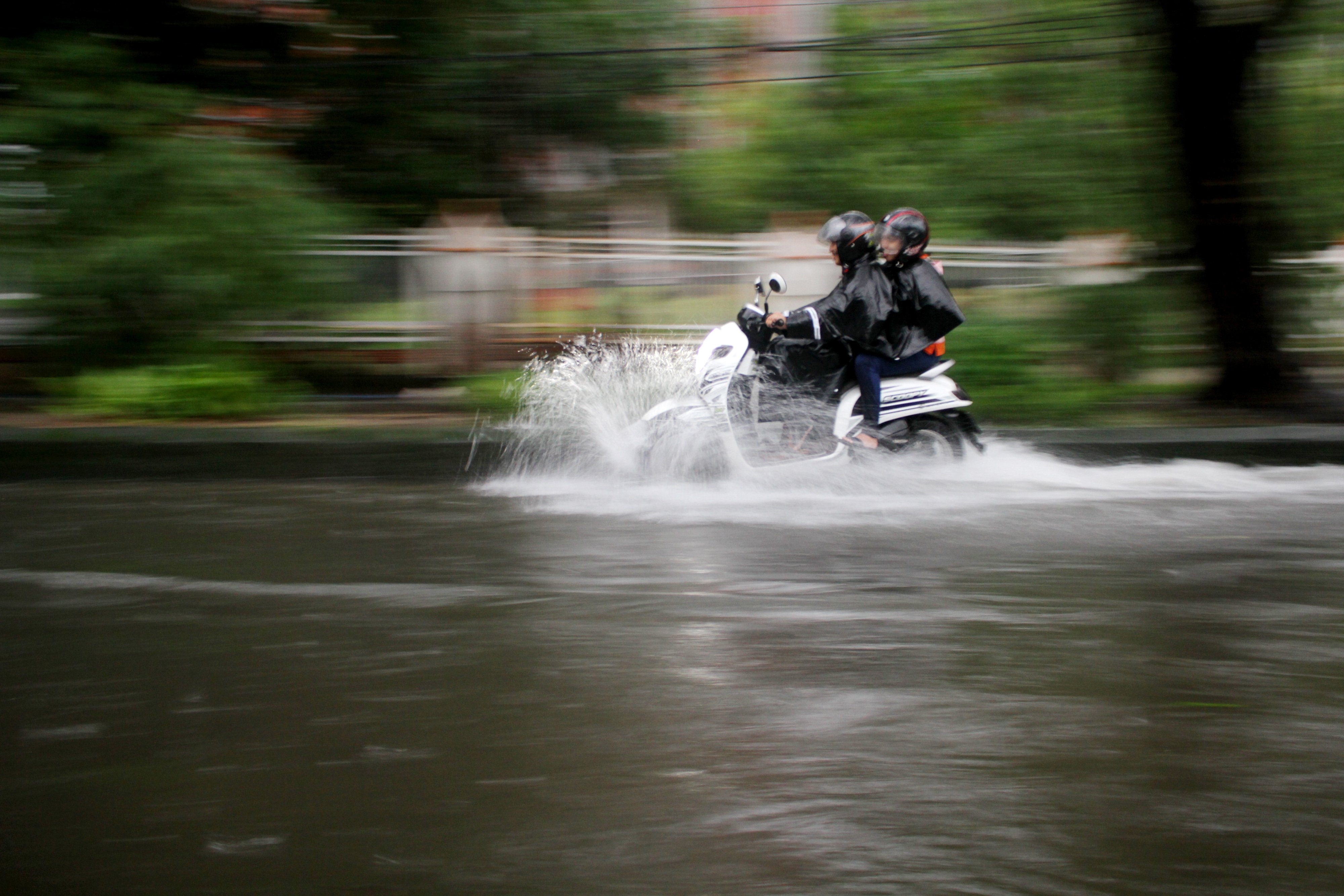 Pengendara motor menerobos banjir di Kota Makassar, Sulawesi Selatan, Minggu (17/1)