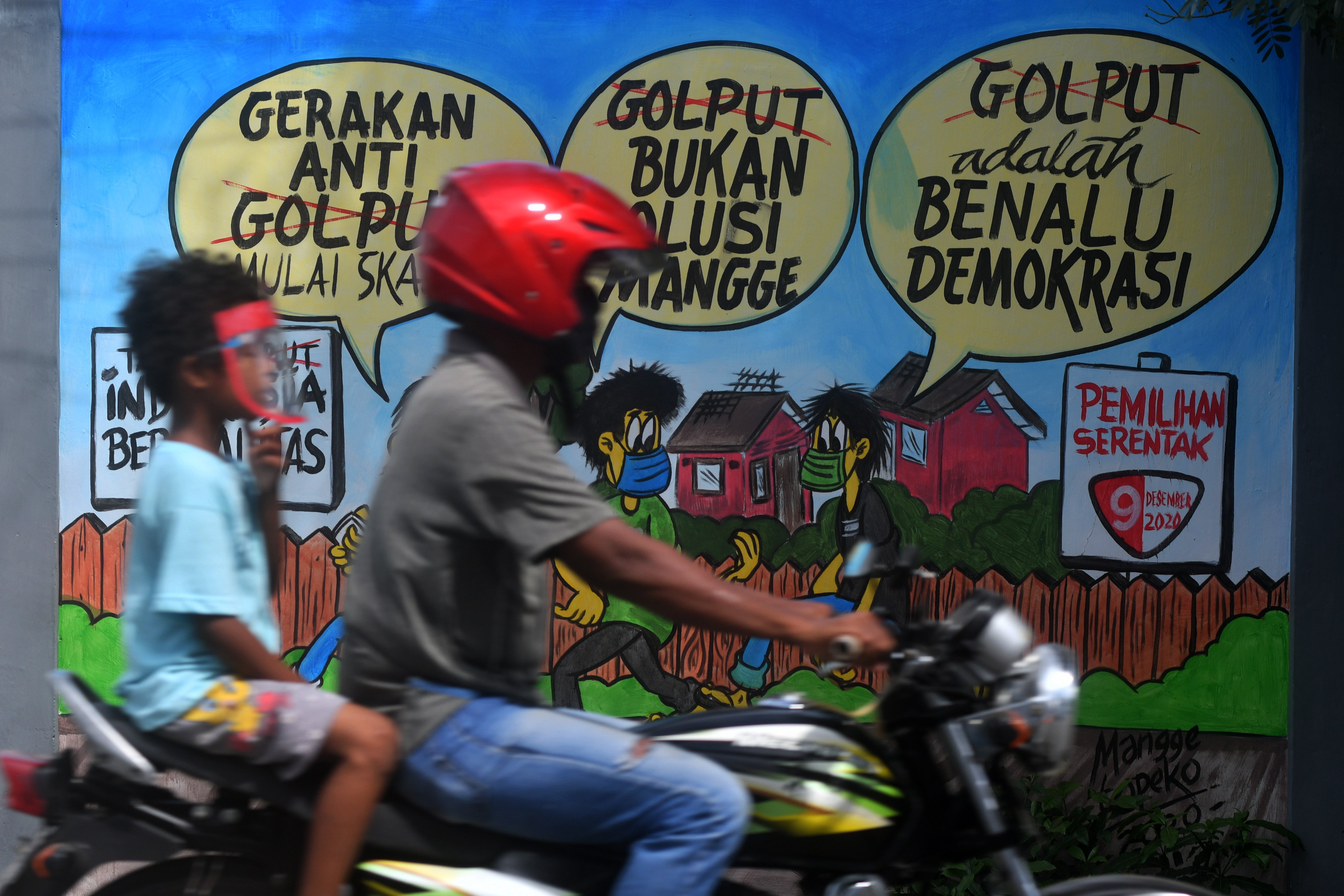 Pengendara motor lewat di depan mural terkait pesta demokrasi di Sulawesi Tengah.