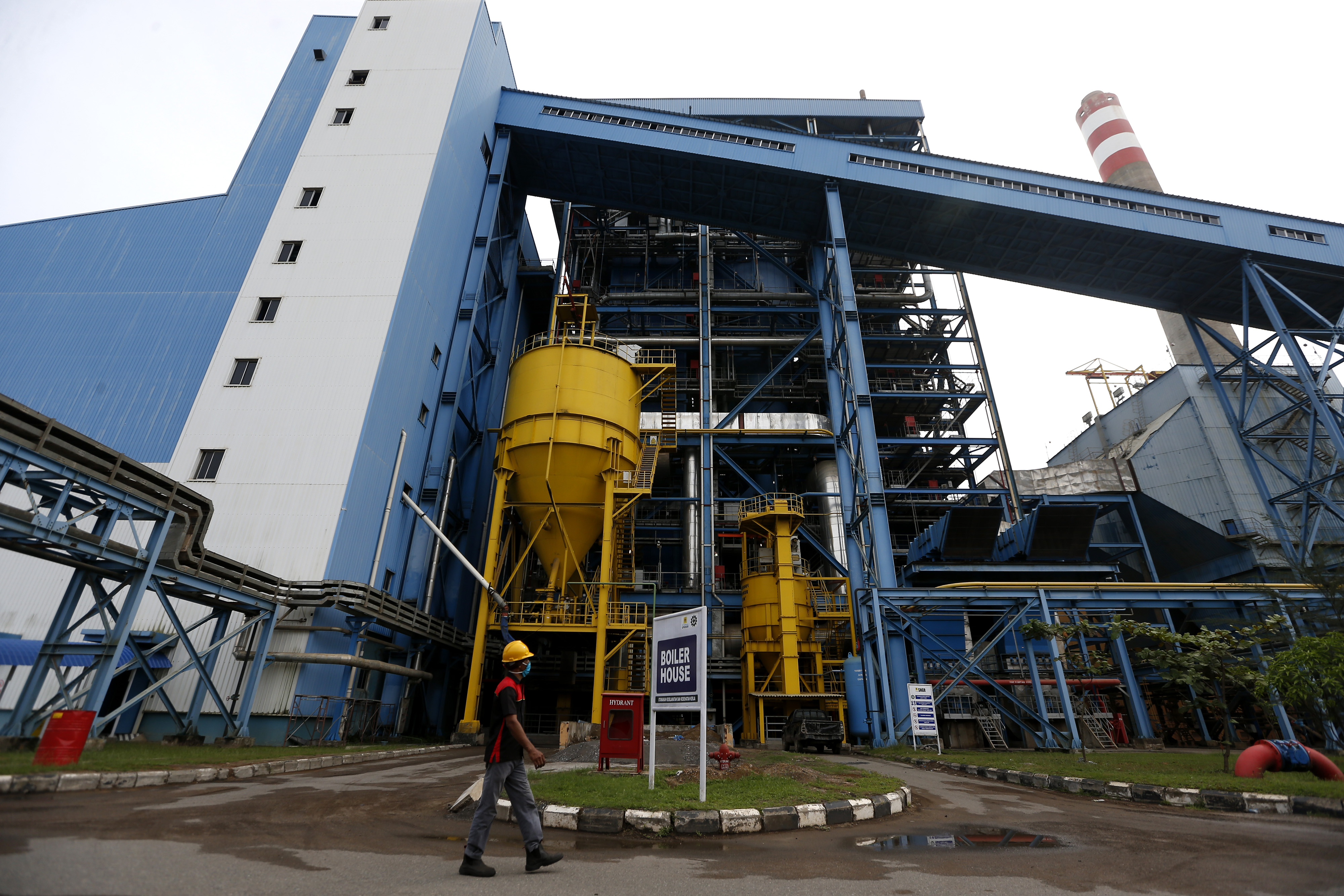 Pekerja melintas di depan tempat penguapan Pembangkit Listrik Tenaga Uap (PLTU) Nagan Raya, di Nagan Raya, Aceh, Senin (28/9/2020)