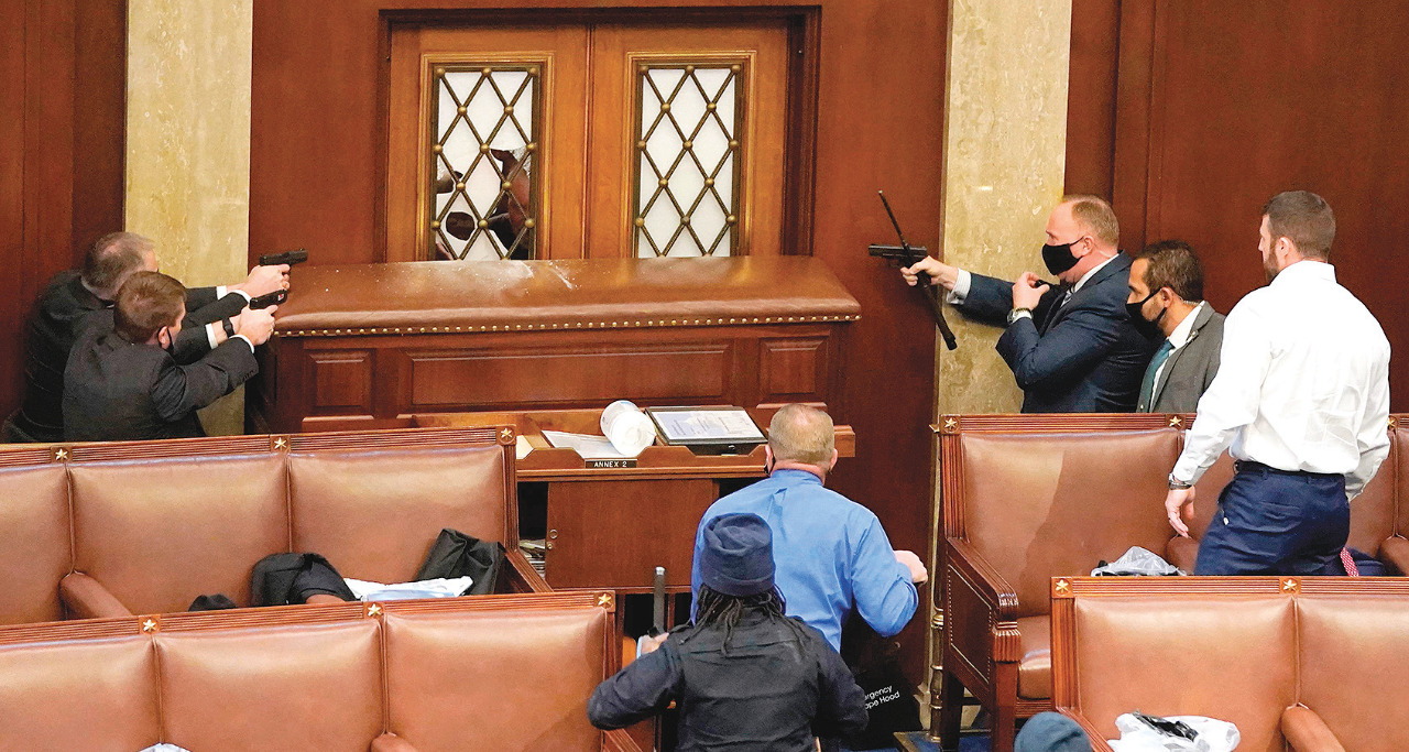 Aparat kepolisian menodongkan pistol ke arah pendukung Donald Trump yang berusaha masuk ke House Chamber di Gedung Capitol, Washington DC.
