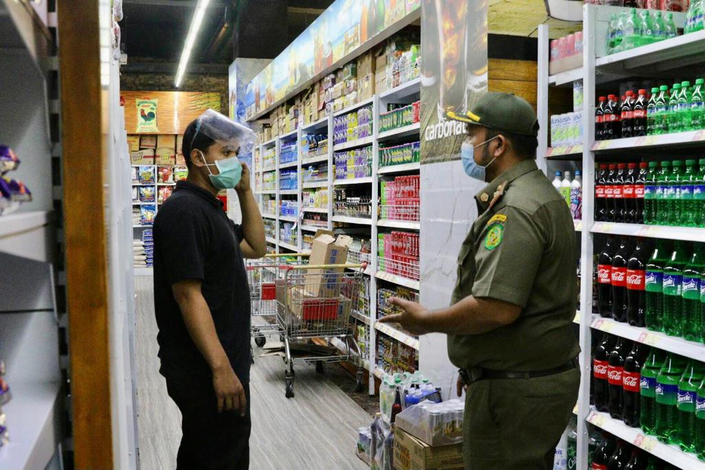 Seorang petugas Satpol PP Kota Medan memperingati karyawan Smarco Superstore  Medan yang kedapatan tidak mengenakan sarung tangan.