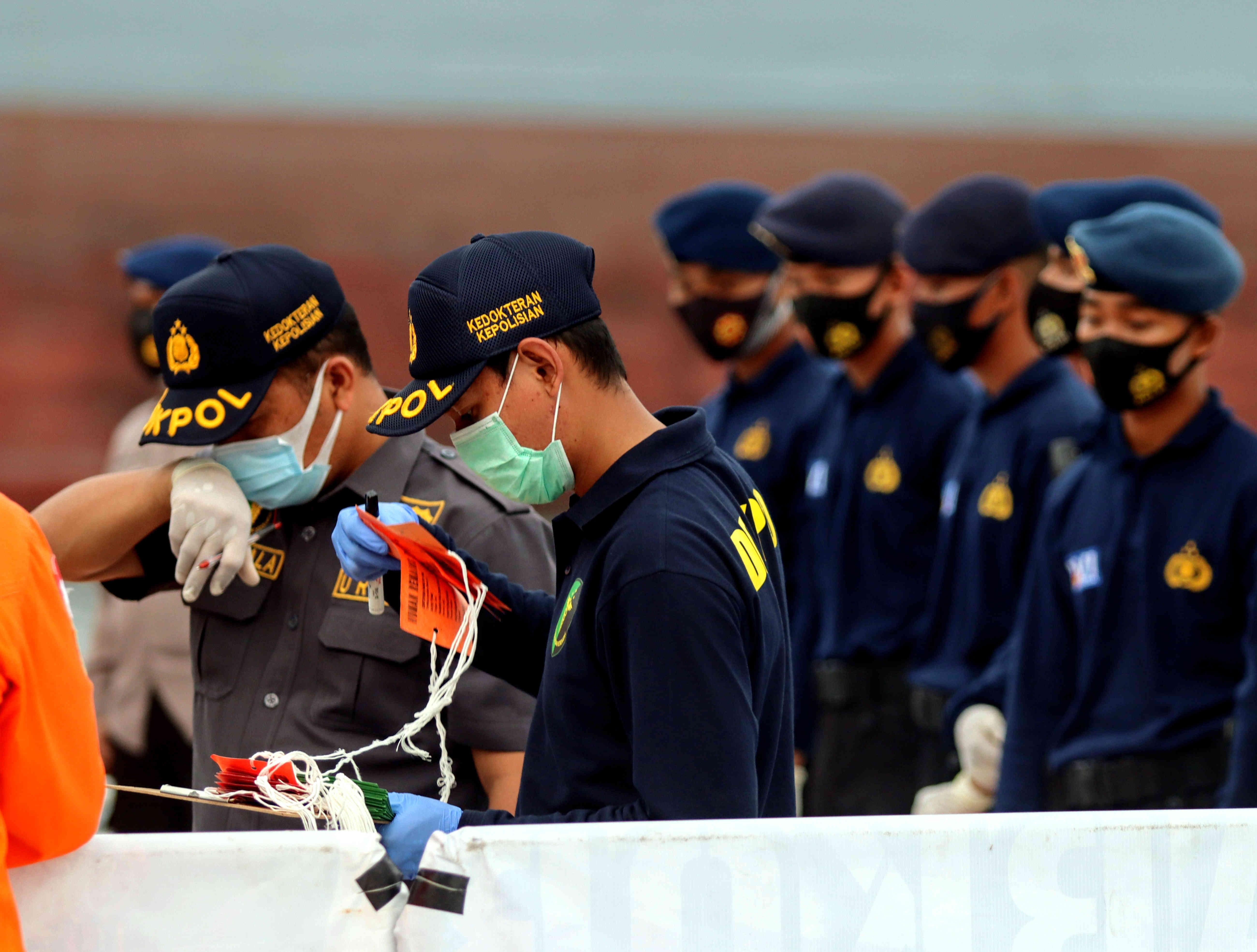  Petugas menurunkan dan memeriksa bagian pesawat dan bagian tubuh korban pesawat Sriwijaya Air SJ-182 di Tanjung Priok, Jumat (15/1).