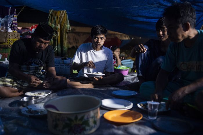 Pengungsi gempa Sulawesi Barat berada di tenda sedang menyantap makan malam.