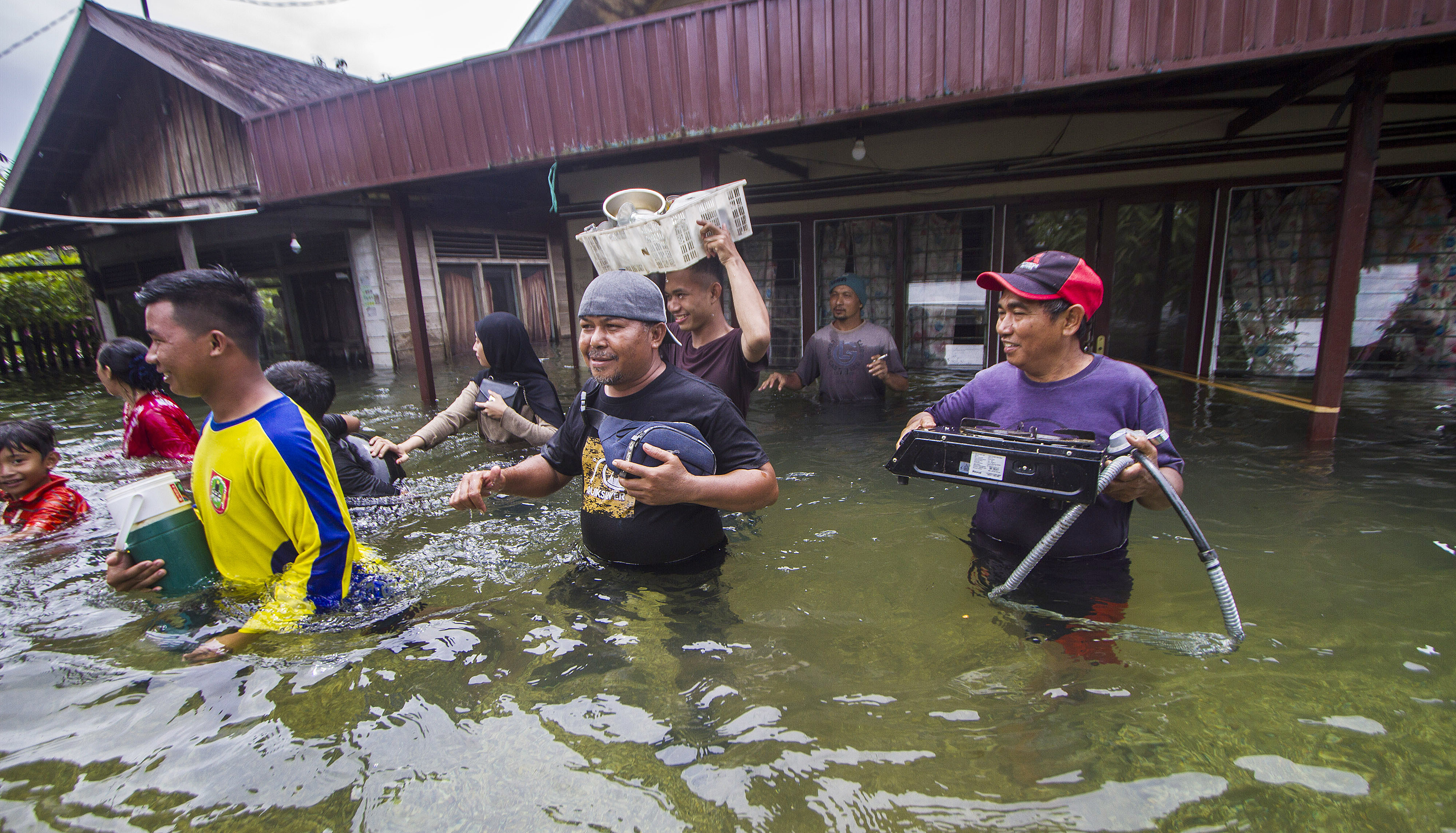 Warga menyelamatkan barang dari rumah yang terendam banjir di Desa Banua Raya di Kabupaten Tanah Laut, Kalimantan Selatan, Senin (11/1/2021)