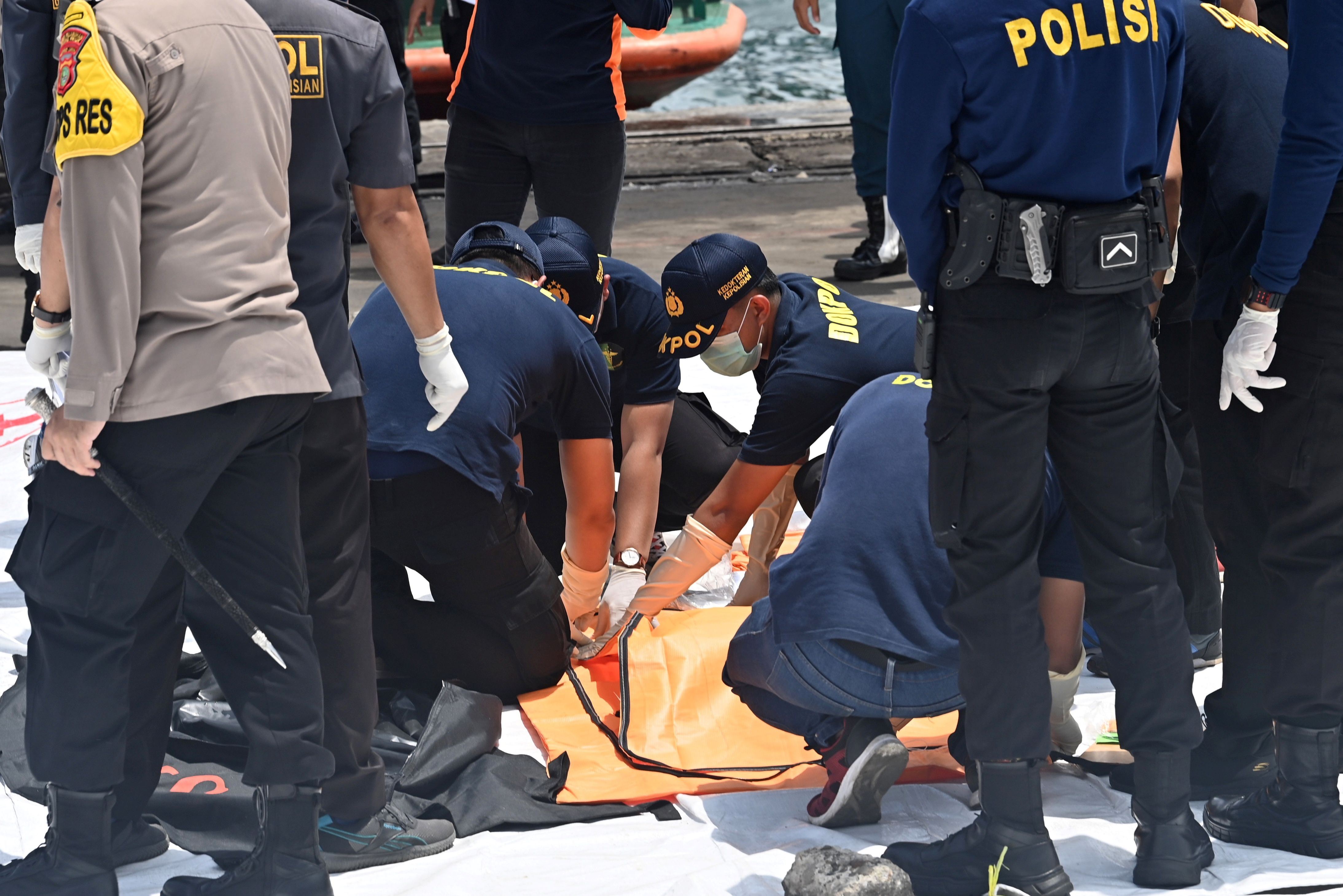 Polisi RI memeriksa jenazah korban di pelabuhan Tanjung Priok, Jakarta Utara, Senin (11/1).