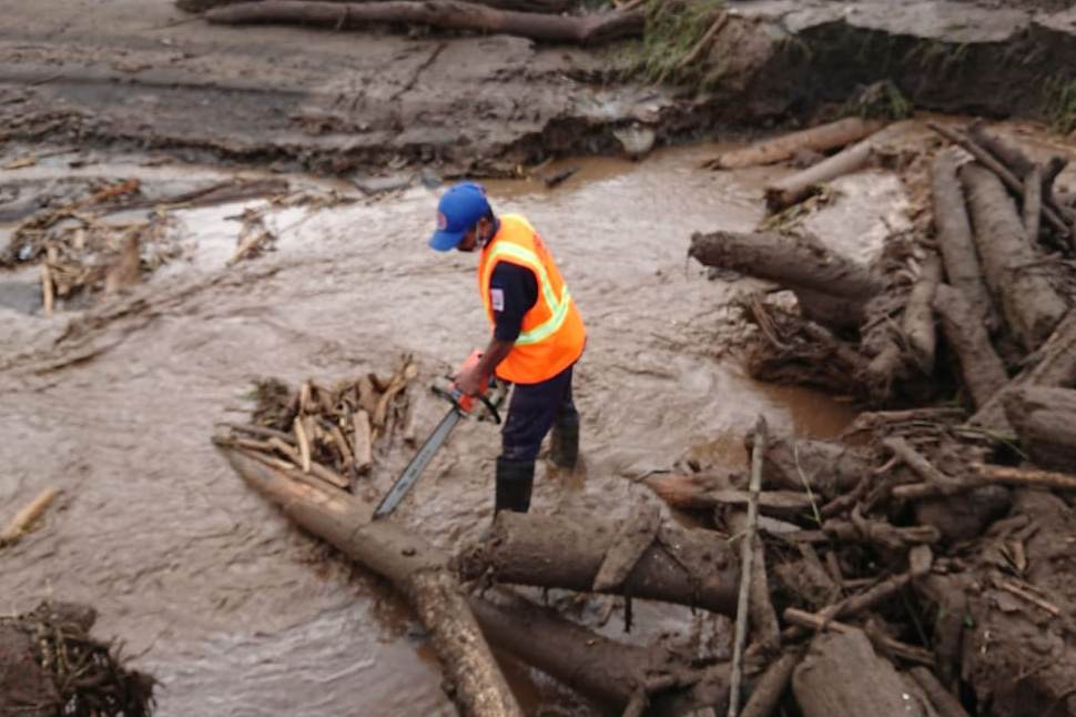 Petugas gabungan BPBD, TNI, dan warga membersihkan potongan kayu gelondongan yang menutup Sungai Sambong.