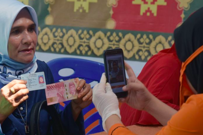 Petugas memotret warga saat serah terima dana bantuan sosial (Bansos) tunai di Kota Pekanbaru, Riau, Jumat (8/5).  