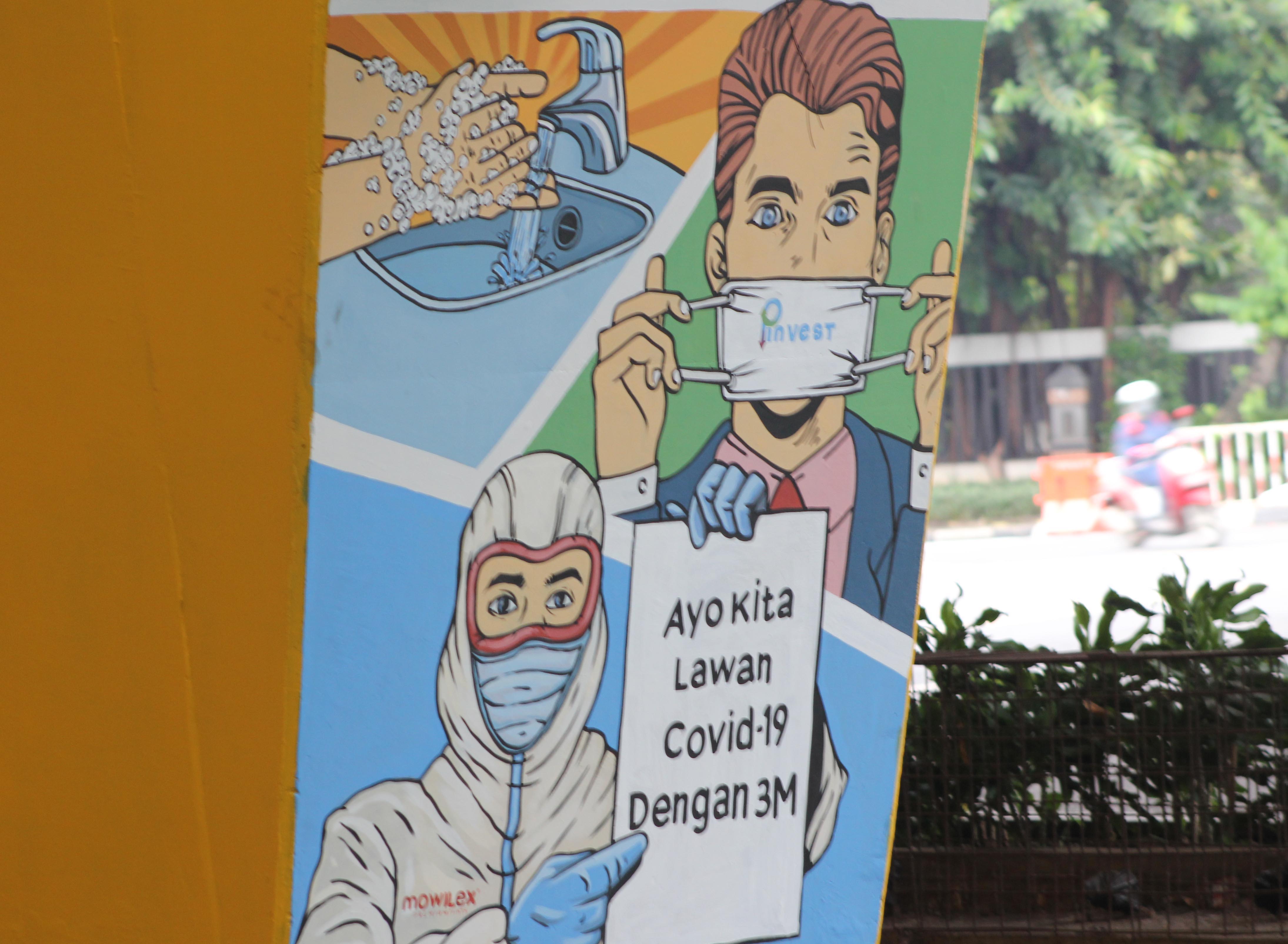 Pengendara melintas didepan Mural sosialisasi pencegahan penularan virus Covid-19 di Jakarta.