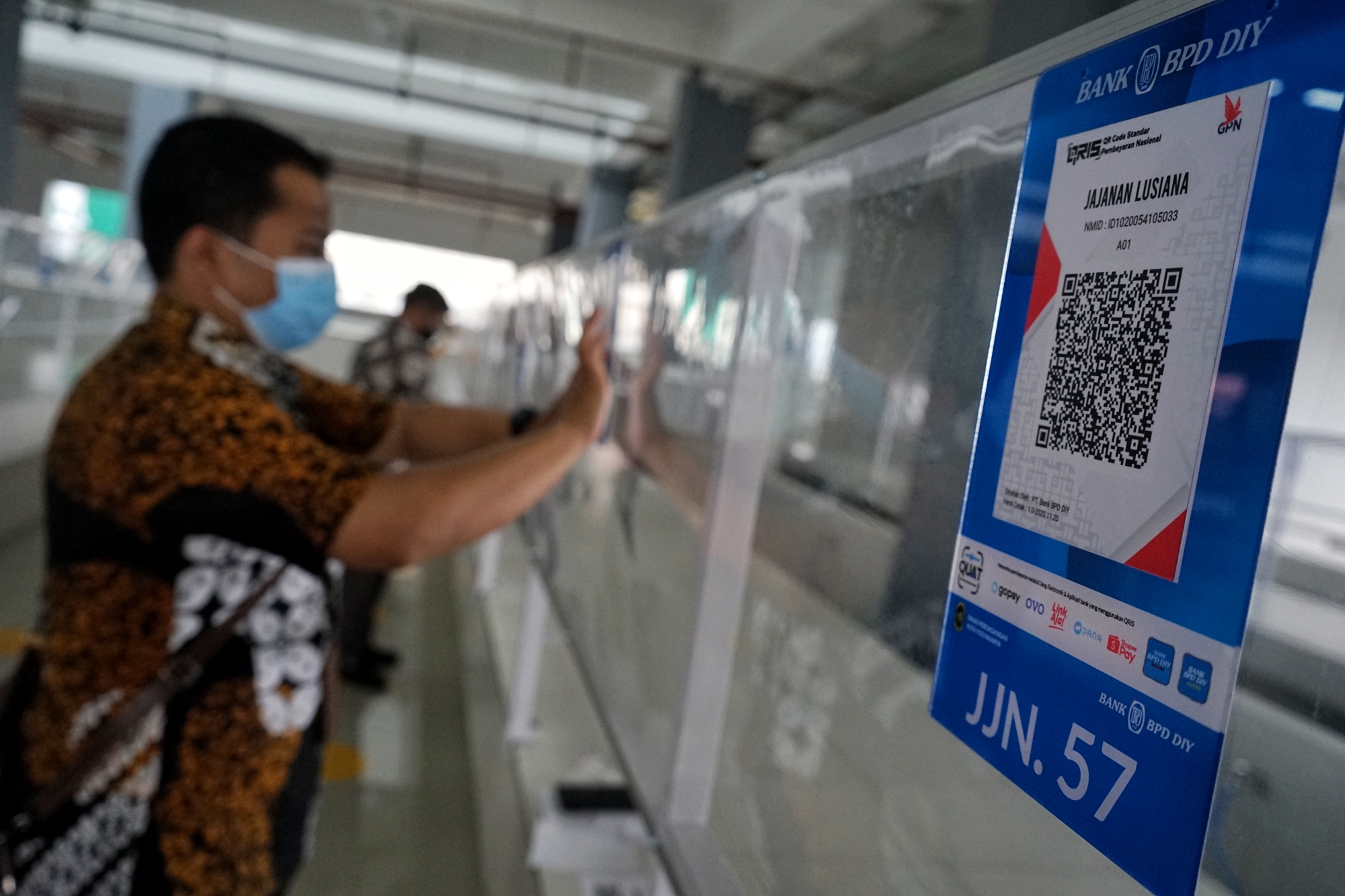 Pegawai menempelkan kode QRIS untuk transaksi non tunai di Pasar Prawirotaman, Yogyakarta, Jumat (4/12/2020). 