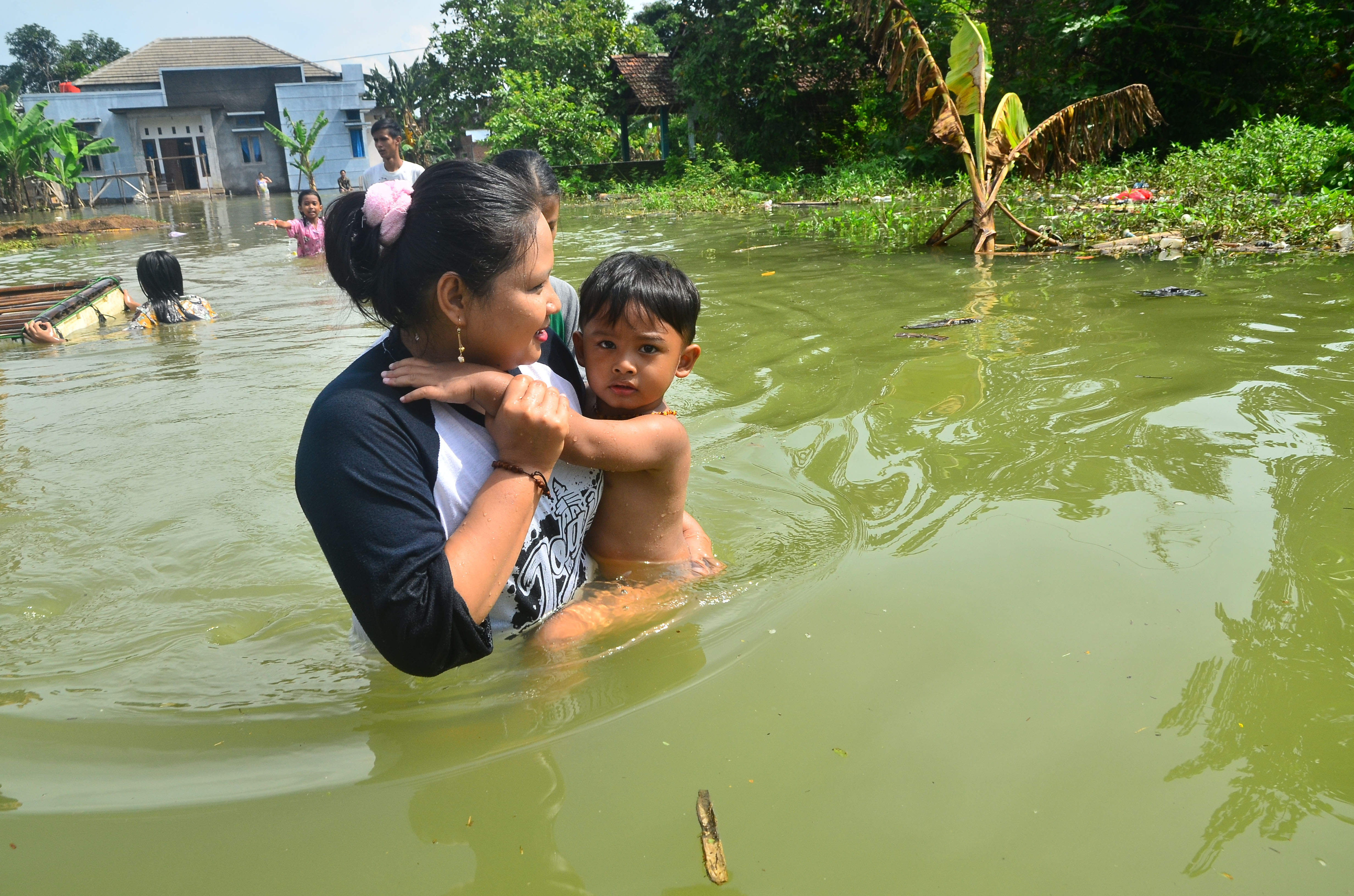 Warga melintasi jalan yang tergenang banjir akibat jebolnya tanggul Sungai Gelis di Desa Setrokalangan, Kudus, Jawa Tengah, kemarin.