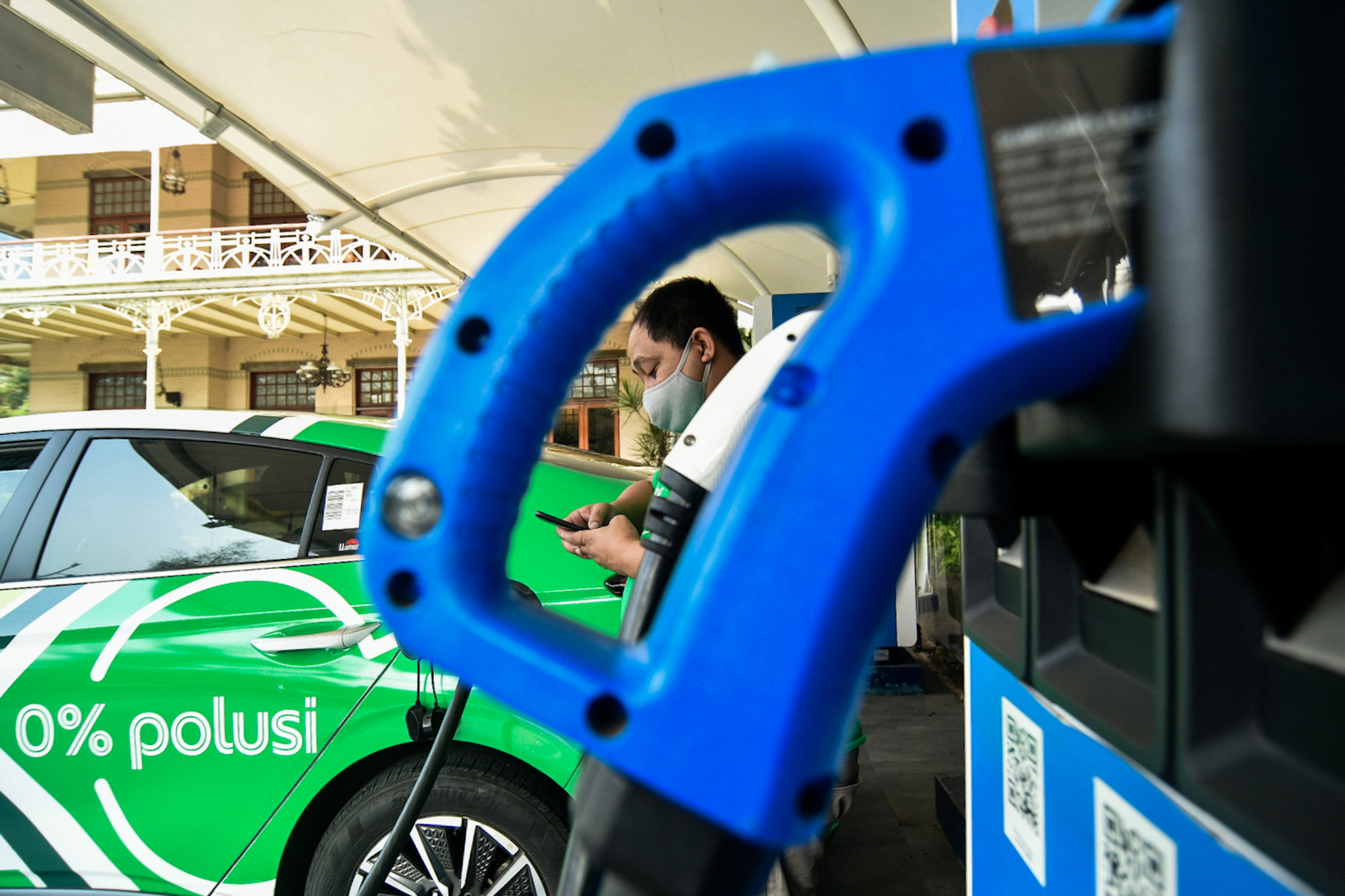 Pengemudi kendaraan listrik melakukan pengisian daya di SPKLU PLN.