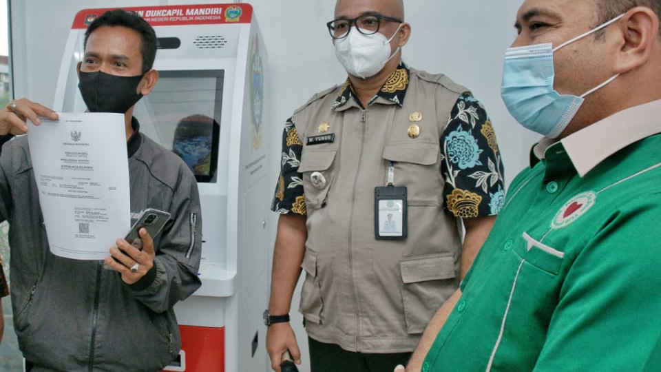 Seorang warga memperlihatkan dokumen kependudukan yang didapatkannya dari mesin Anjungan Dukcapil Mandiri (ADM) di Kecamatan Medan Marelan.
