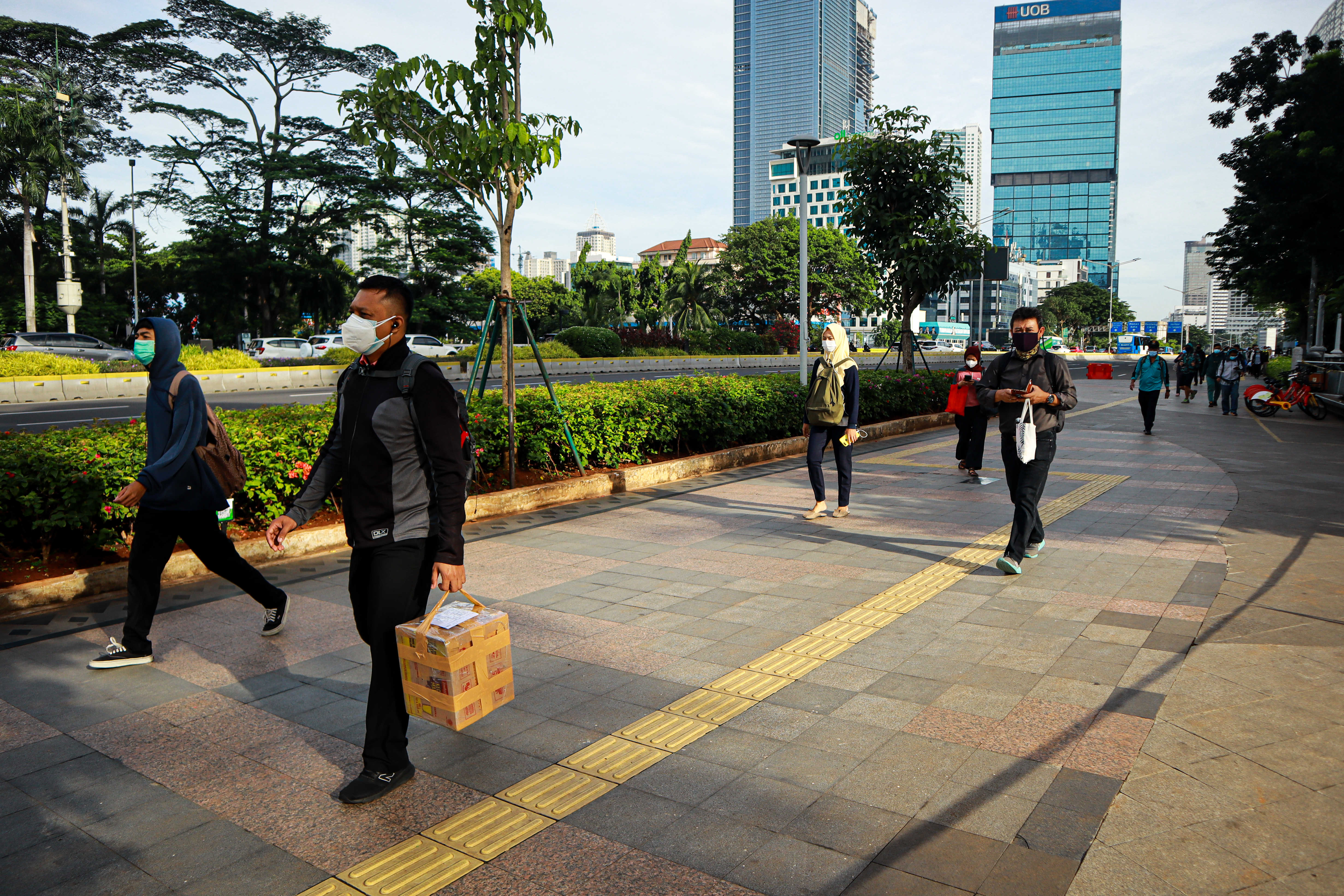 Pekerja berjalan di kawasan Jenderal Sudirman, Jakarta, Senin (4/1). Pemprov DKI Jakarta memberlakukan kembali PSBB 4-21 Januari 2021.