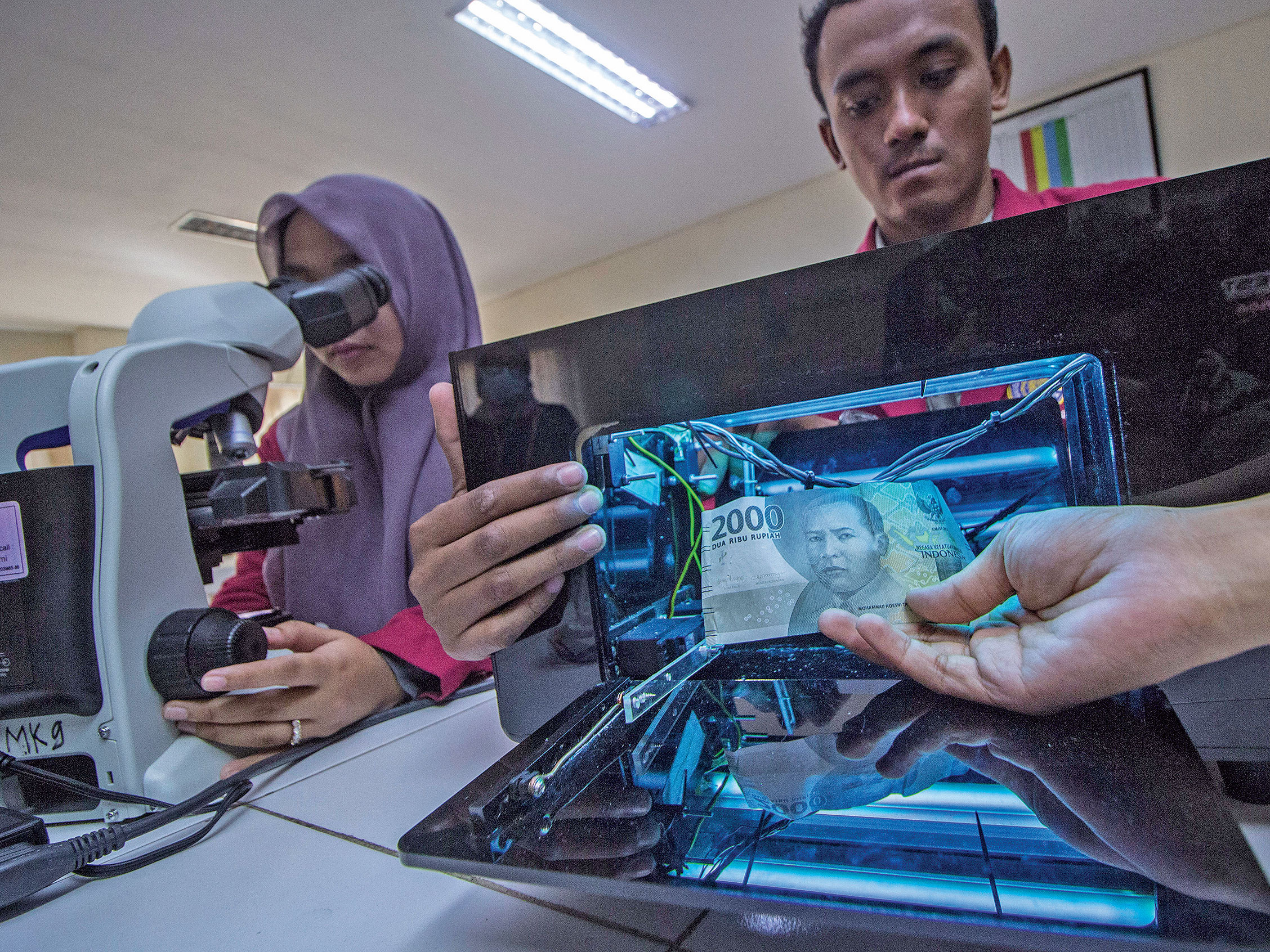 BOX COVID-19: Mahasiswa S-1 Teknik Elektro Universitas Muhammadiyah Surabaya (UMS) Iman Ramadhan (kanan) menunjukkan alat sterilisasi uang 