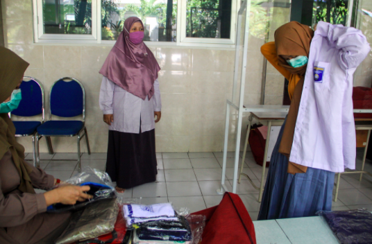 Seorang siswa mencoba seragam sekolah saat mengambil seragam siswa baru di SMA Muhammadiyah 2 (Smamda) Sidoarjo, Jawa Timur, Rabu (10/6).