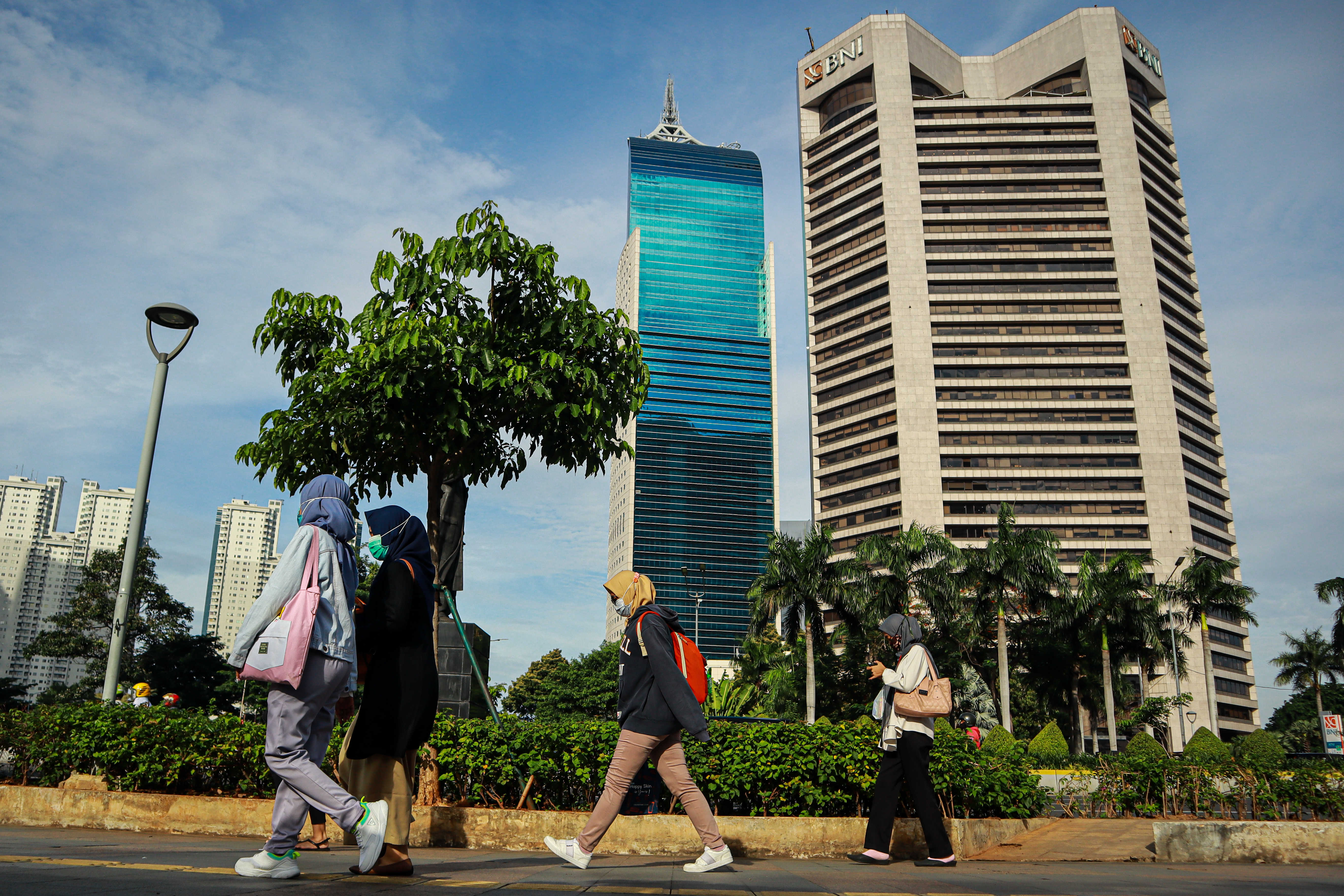 Pekerja kantoran melintas di kawasan bisnis Jalan Jenderal Sudirman, Jakarta