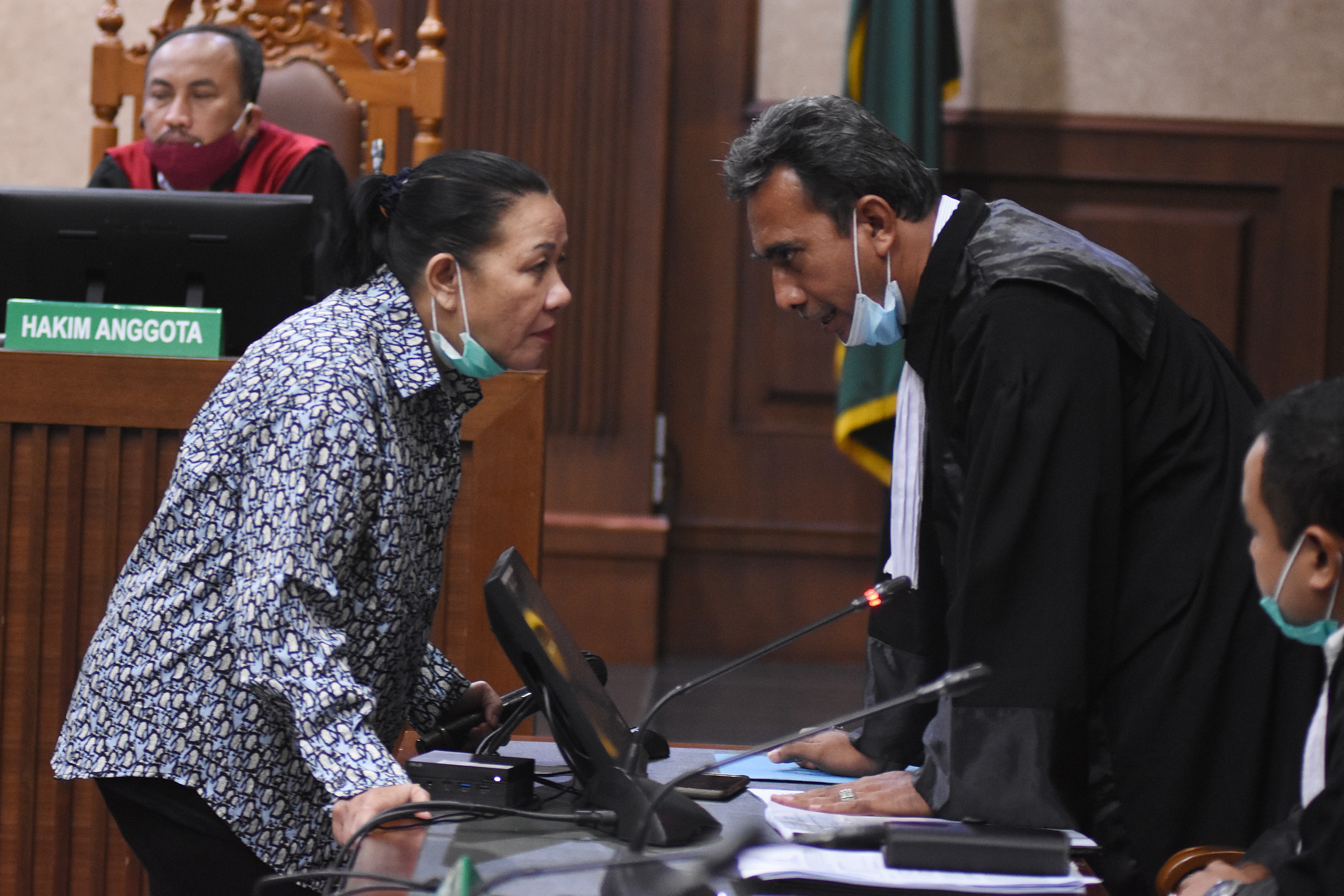 Maria Pauline Lumowa (kedua kiri) berbicara dengan kuasa hukumnya saat sidang perdana dengan agenda mendengarkan pembacaan dakwaan.