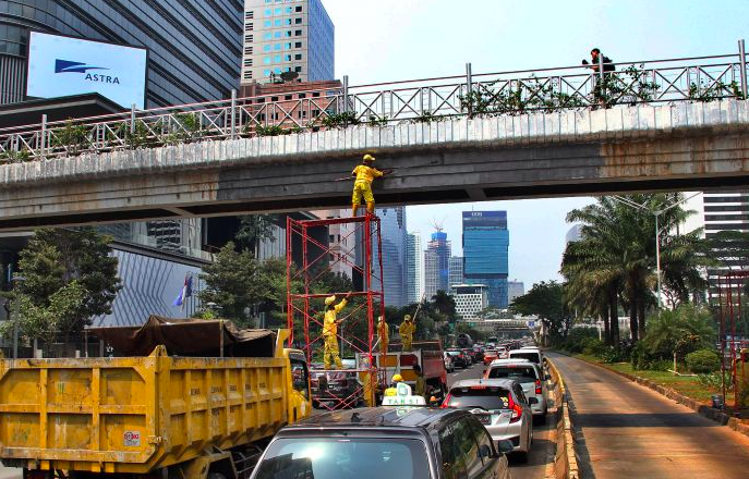 Petugas Dinas Bina Marga DKI Jakarta mengecat JPO tidak beratap di Jalan Jenderal Sudirman, Jakarta Pusat.