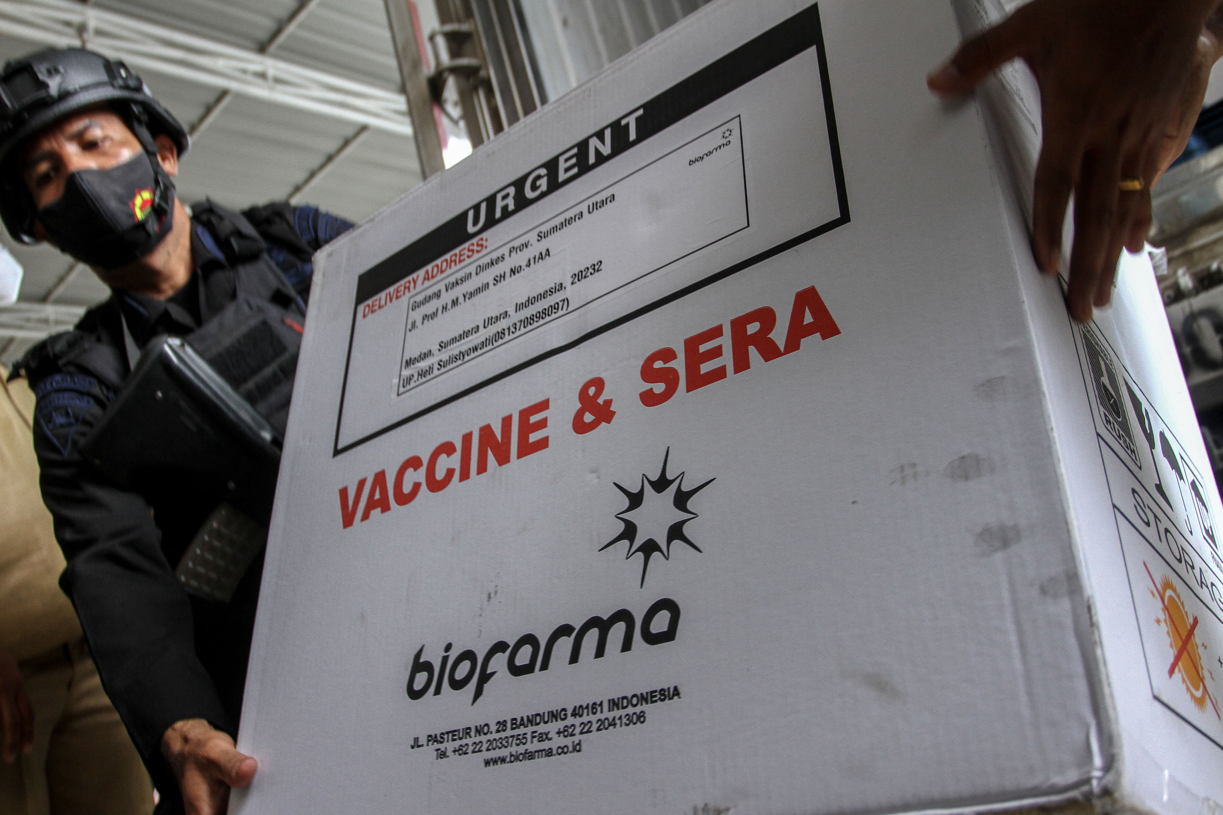  Personel Brimob membantu menurunkan vaksin covid-19 Sinovac saat tiba di gudang Dinas Kesehatan Sumatra Utara, Kota Medan, Sumatra Utara.