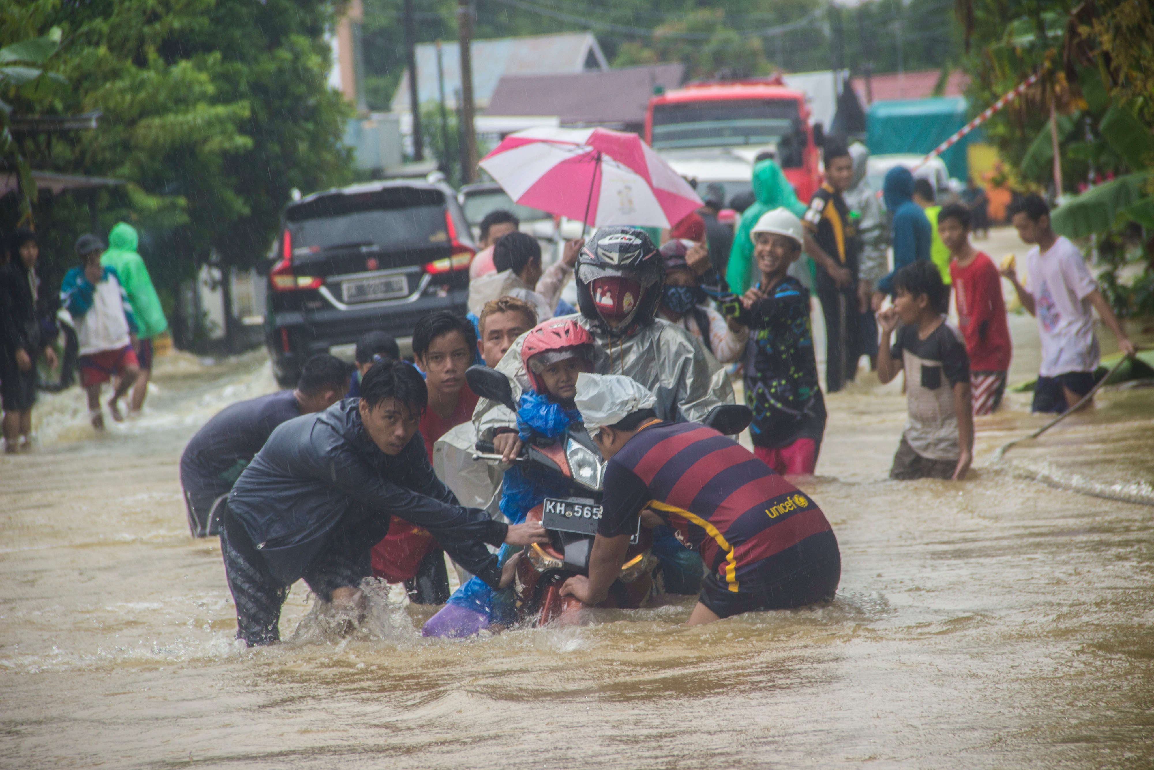 Sejumlah warga membantu pengendara sepeda motor agar tidak terbawa arus saat melintas di Jalan Ahmad Yani, Kabupaten Banjar, Kalsel.