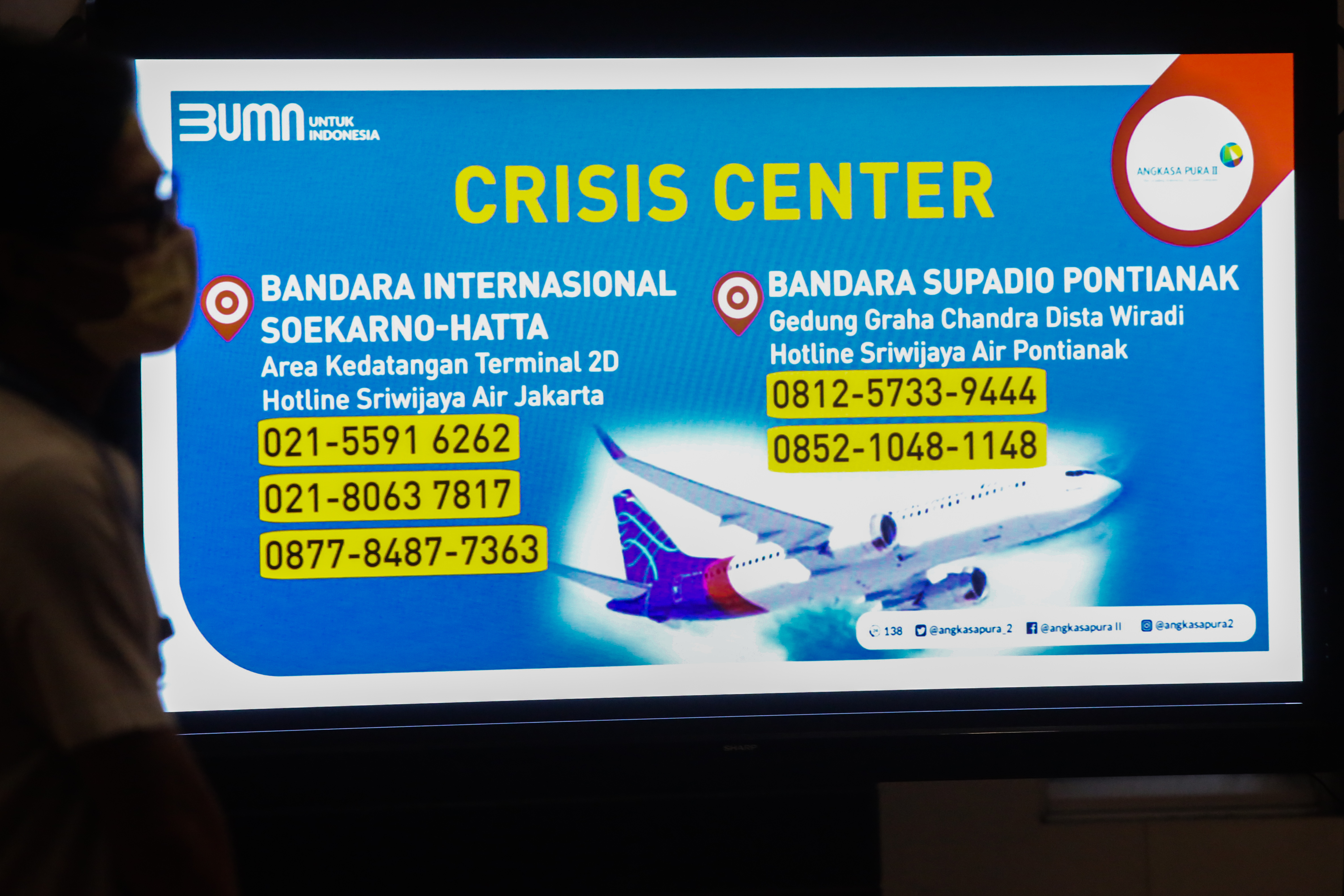 Layar yang menampilkan no telpon di Posko Crisis Center Sriwijaya Air