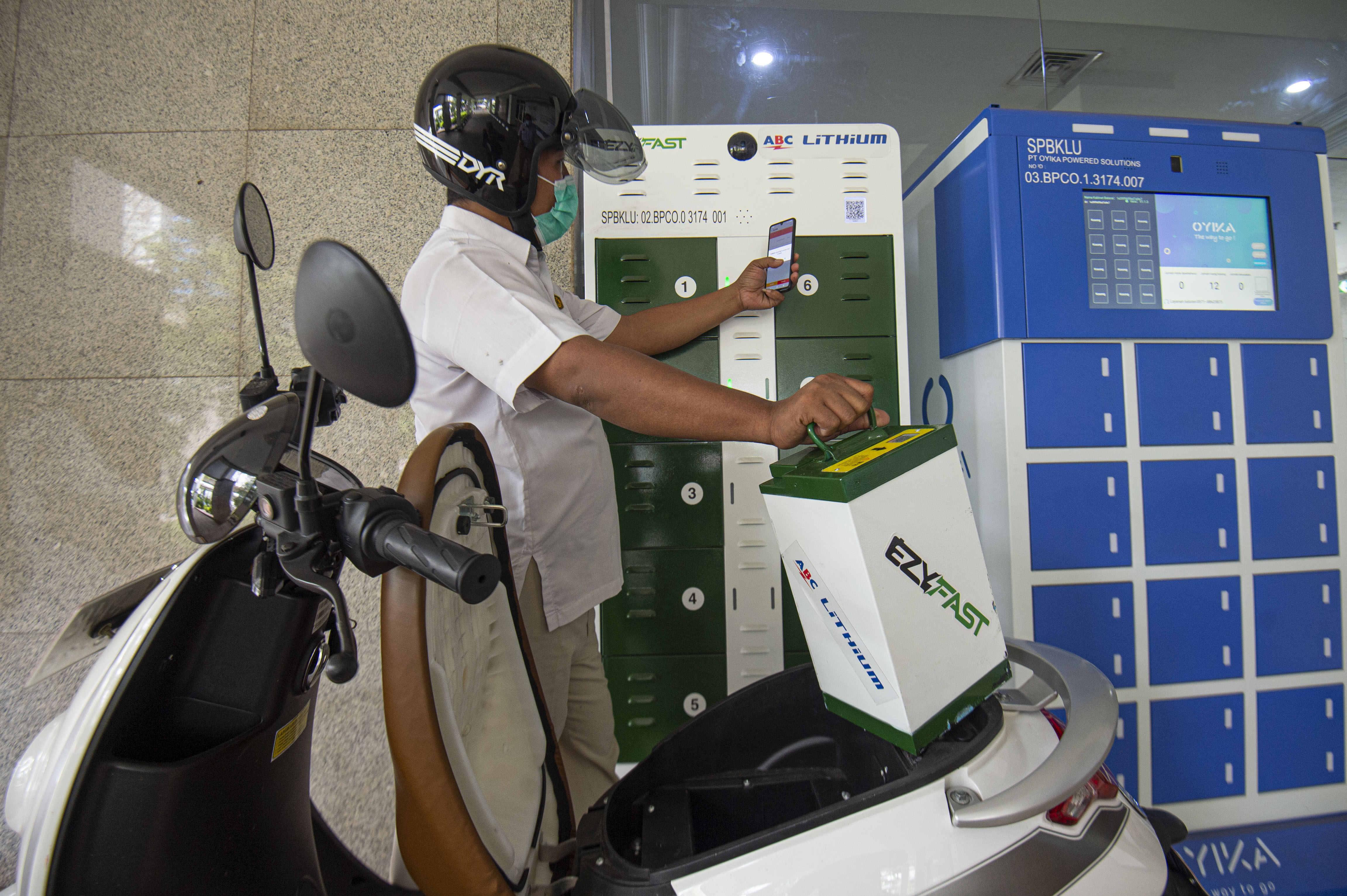 Karyawan mengganti baterai sepeda motor listrik di Stasiun Penukaran Baterai Kendaraan Listrik Umum (SPBKLU), di Jakarta.