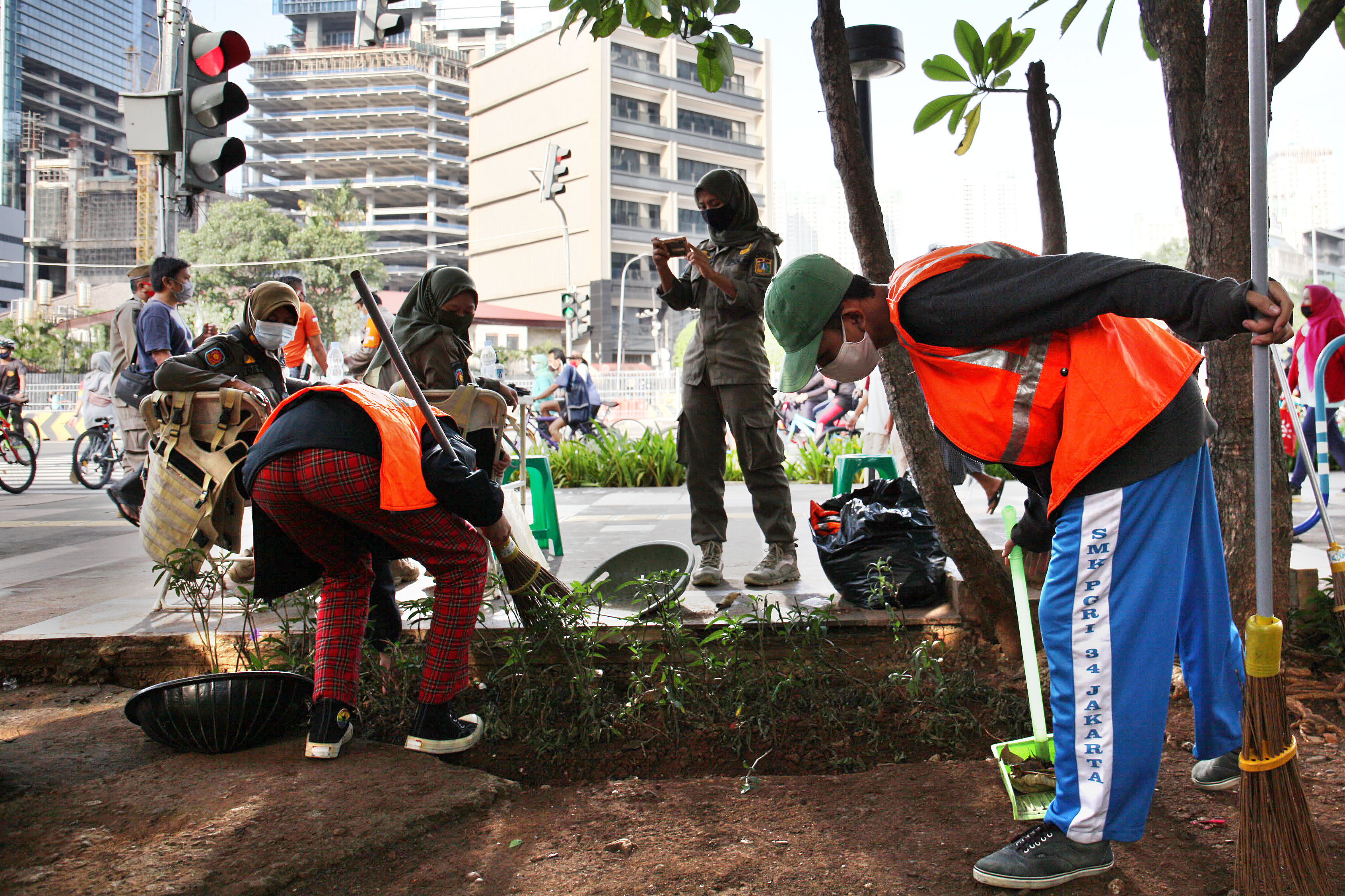 Petugas memberikan sanksi sosial bagi pelanggar protokol kesehatan berupa menyapu jalan di kawasan Sudirman