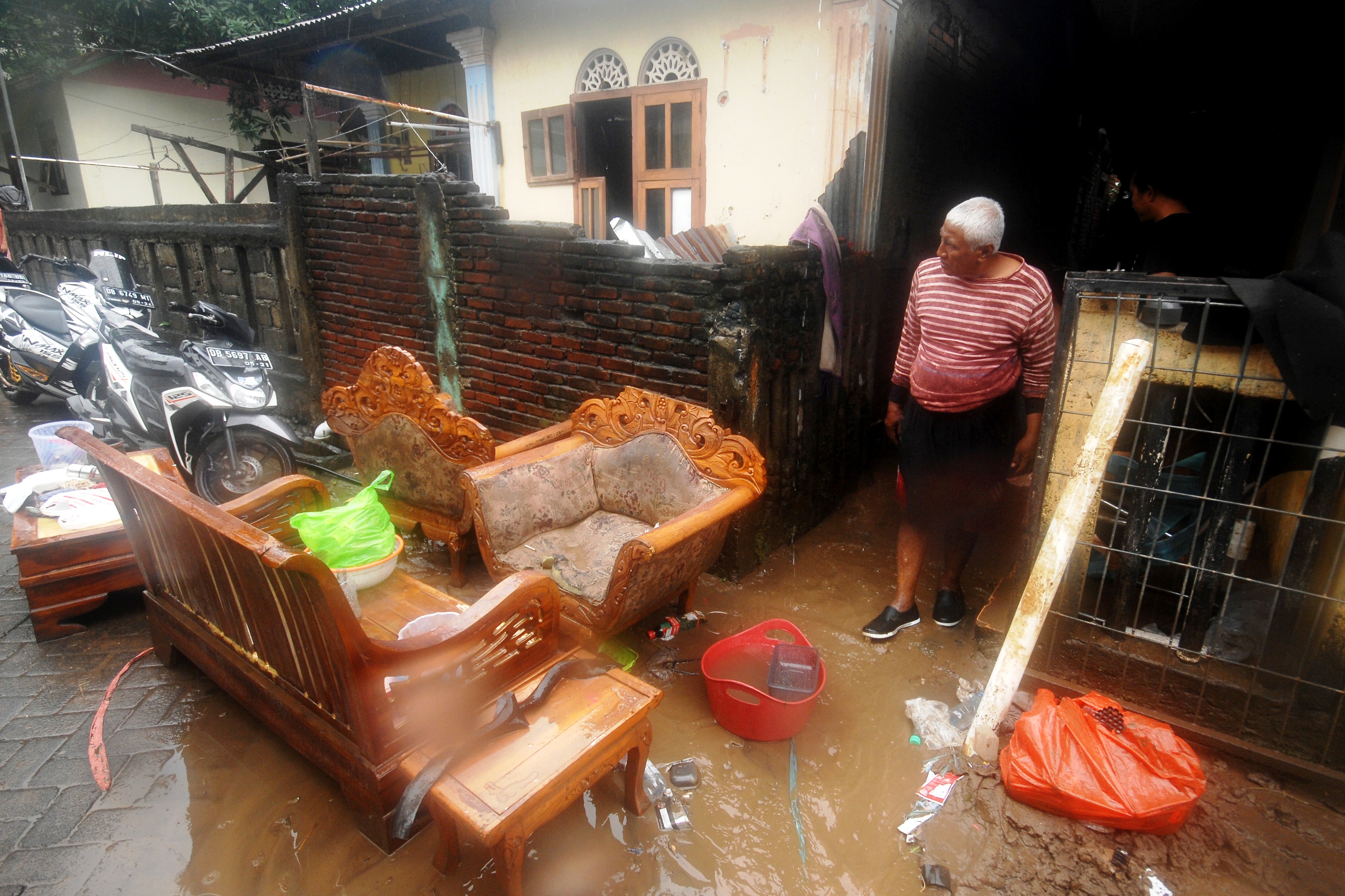 Warga sedang membersihkan rumahnya yang terendam banjir di Kota Manado.