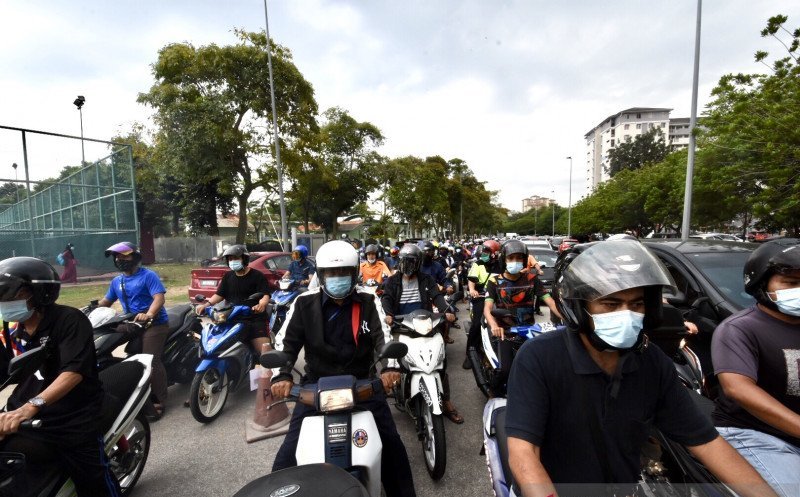 Pengendara lalu lintas di Putrajaya, Malaysia, mengenakan masker. 
