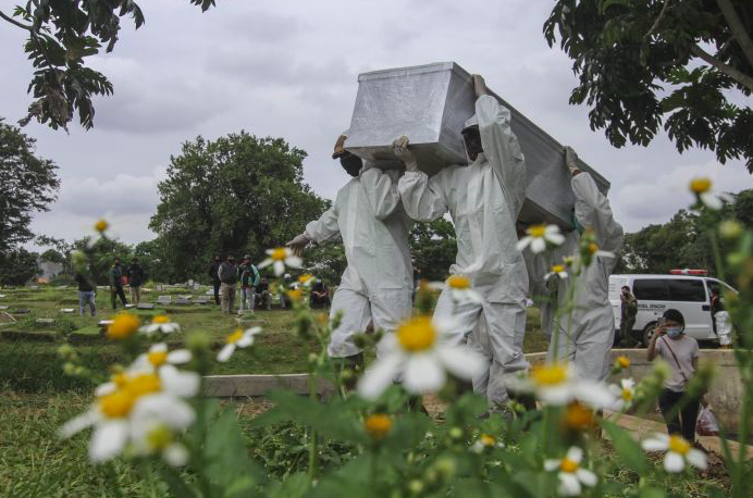 Petugas membawa peti marti yang berisi pasien Covid-19 yang meninggal dunia di TPU Srengseng Sawah, Jakarta