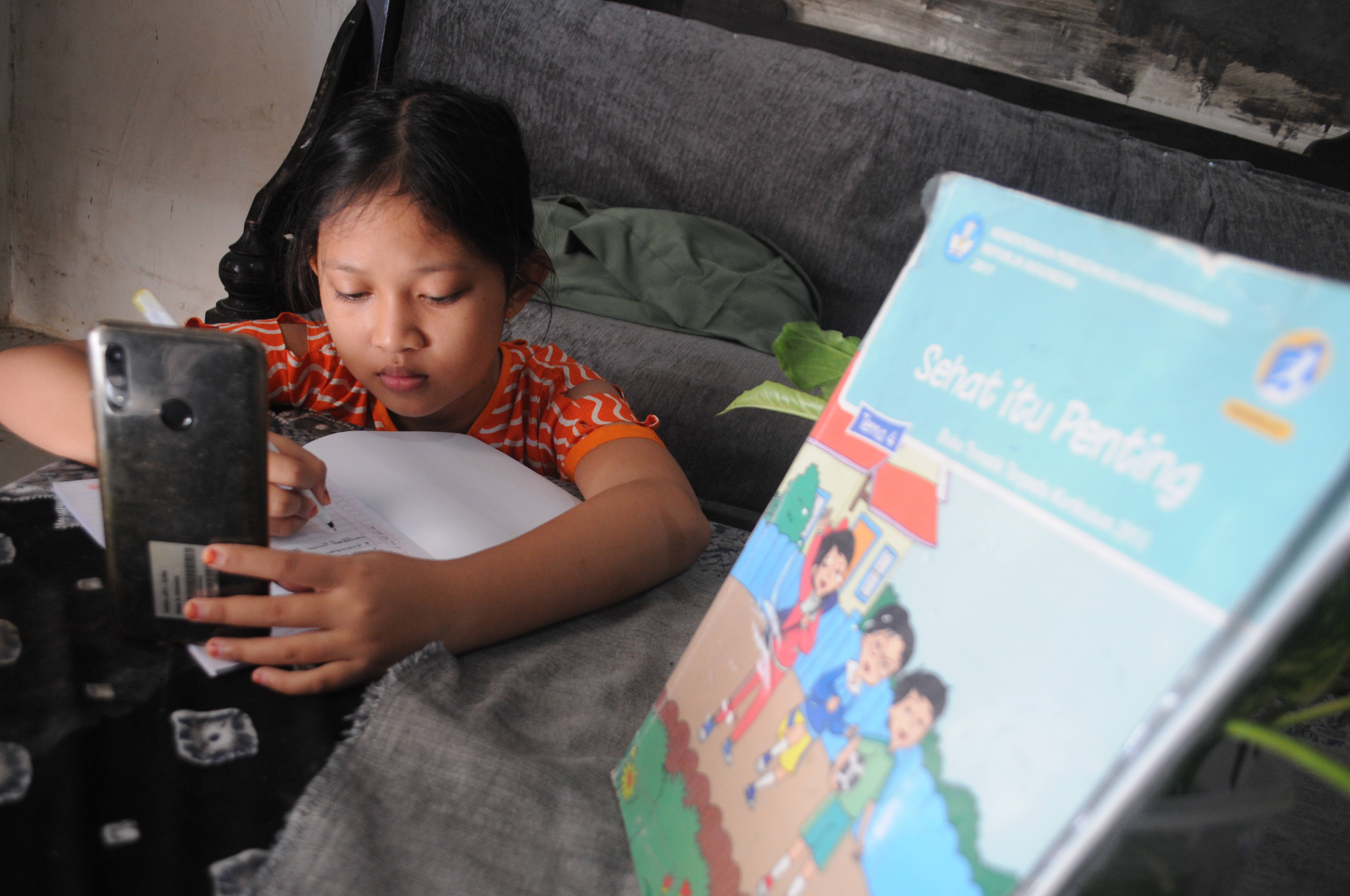 Seorang anak sekolah dasar mengerjakan ujian Penilaian Akhir Semester (PAS) dengan sistem daring 