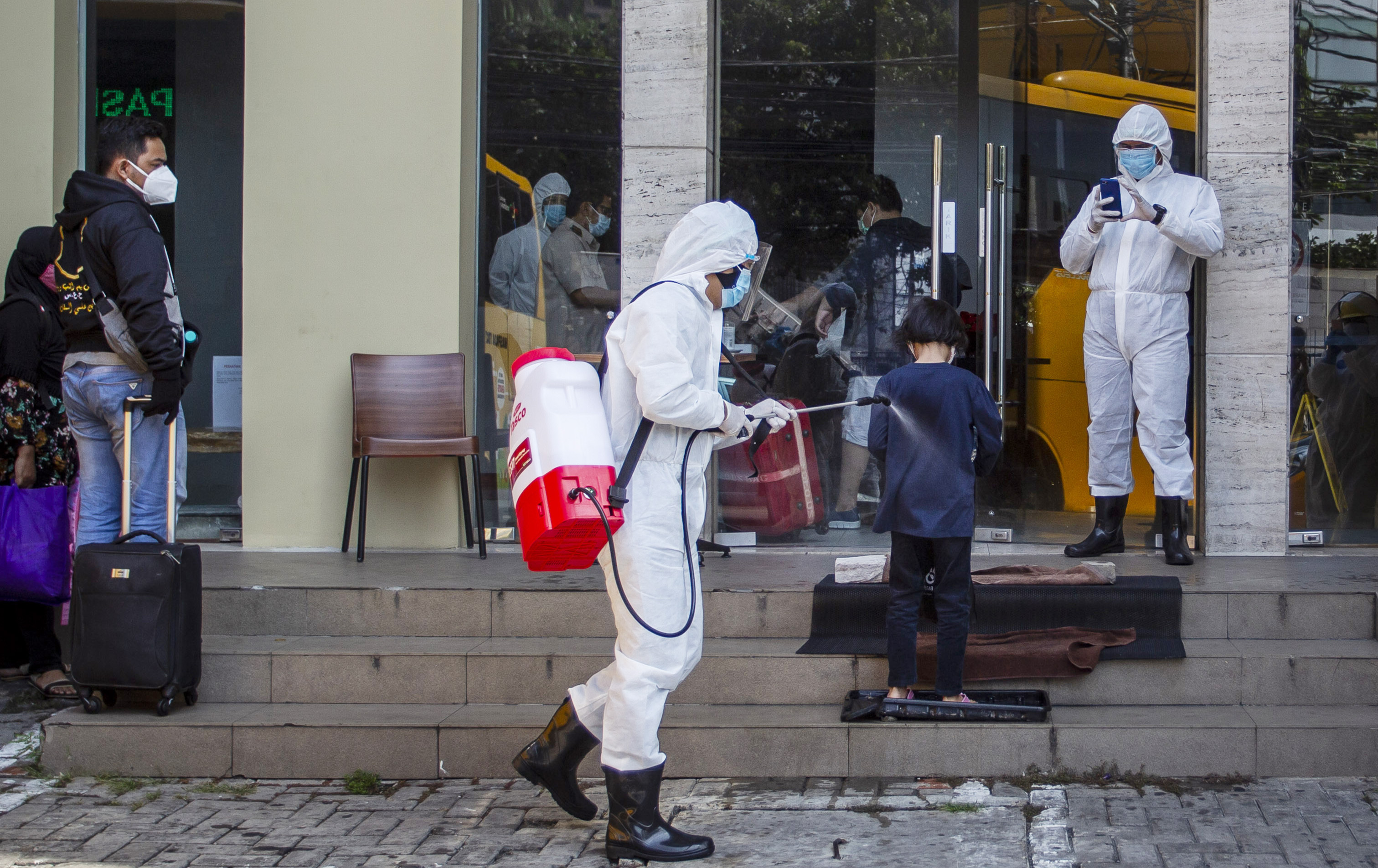 Petugas medis meyemprotkan cairan disinfektan kepada pasien COVID-19 berstatus Orang Tanpa Gejala (OTG) sebelum memasuki hotel 