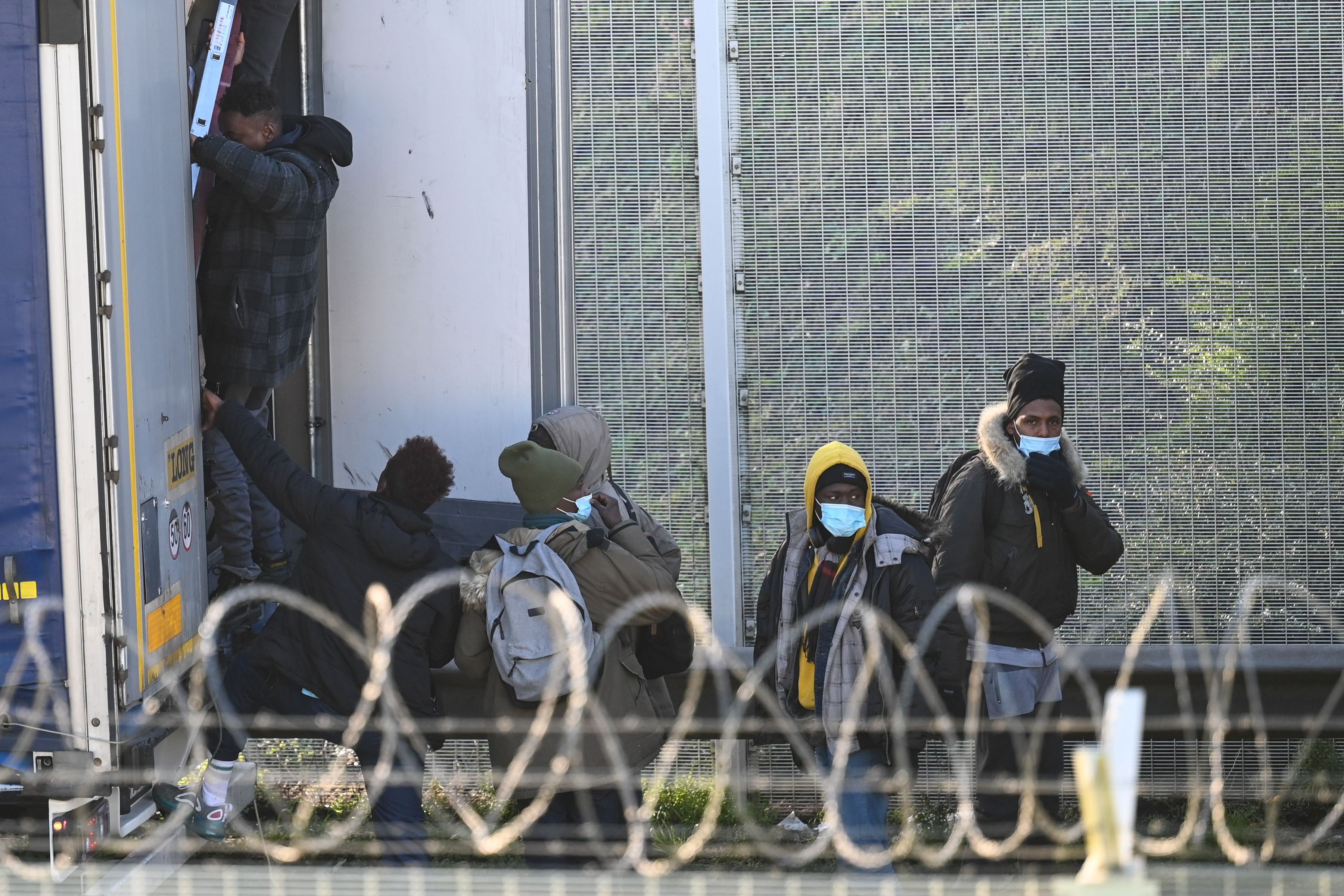 Migran naik ke bagian belakang truk menuju Inggris.