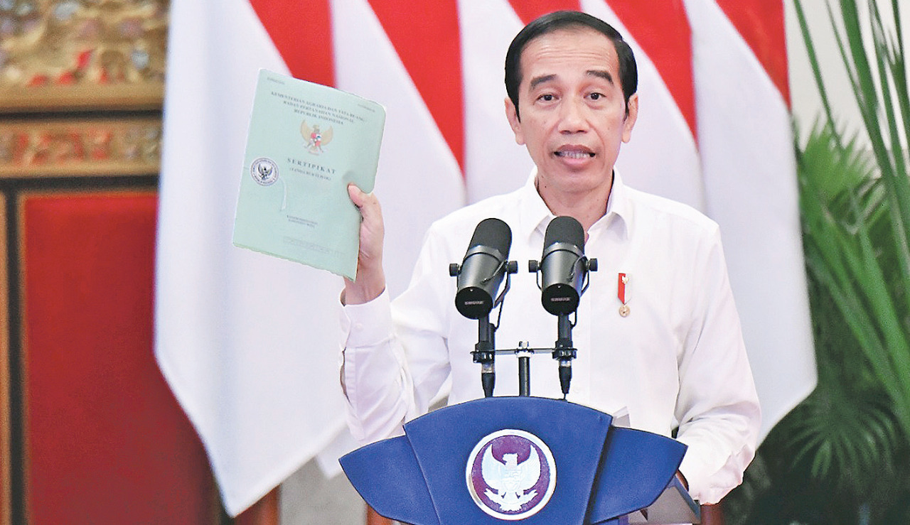 Presiden Joko Widodo memberikan sambutan sambil memegang salah satu sertifikat yang akan diserahkan kepada warga di Istana Negara, Jakarta.