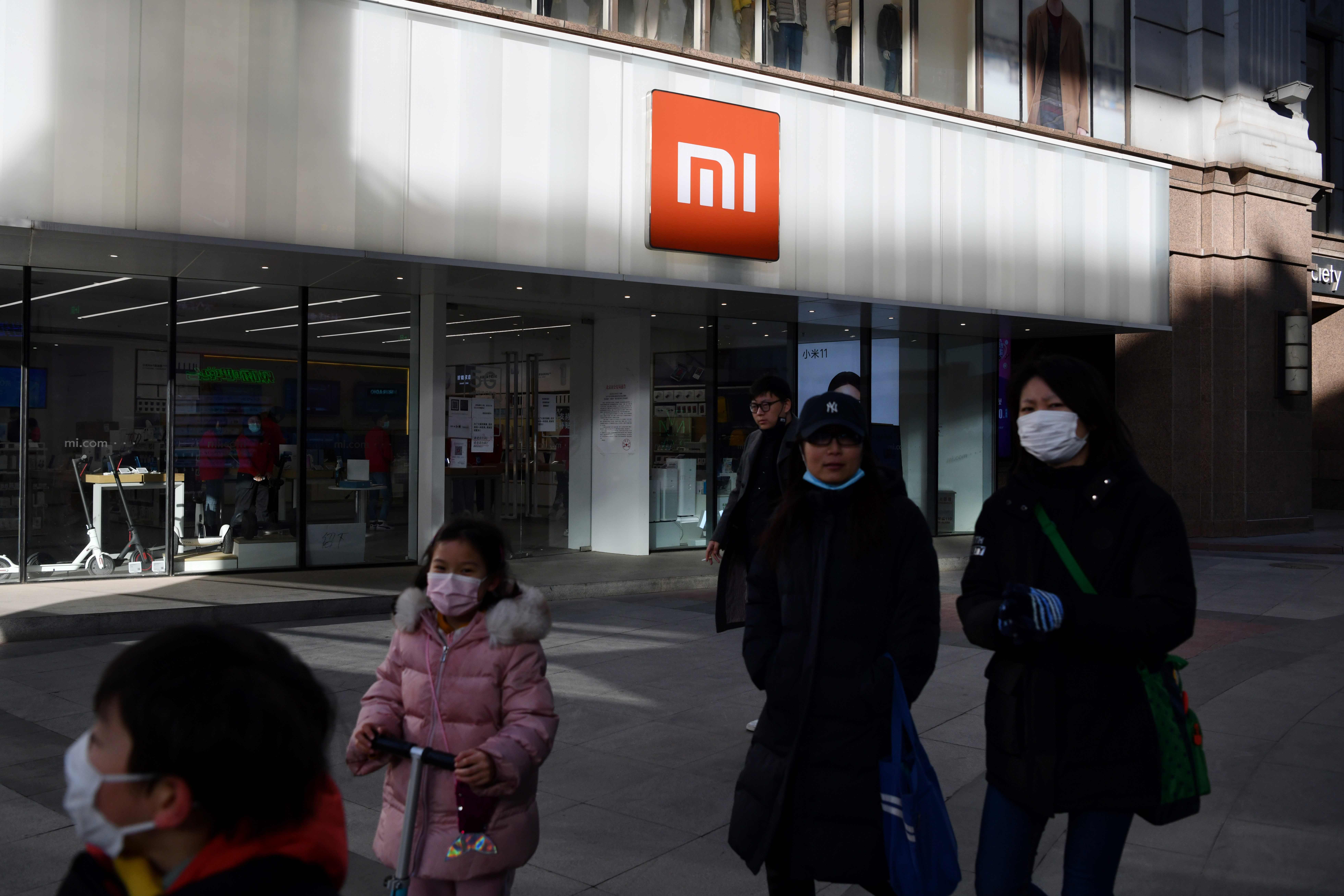 Warga melewwati gerai Xiaomi di Beijing, Tiongkok. Pemerintah AS telah memasukan nama perusahaan Xioami dalam daftar hitam.
