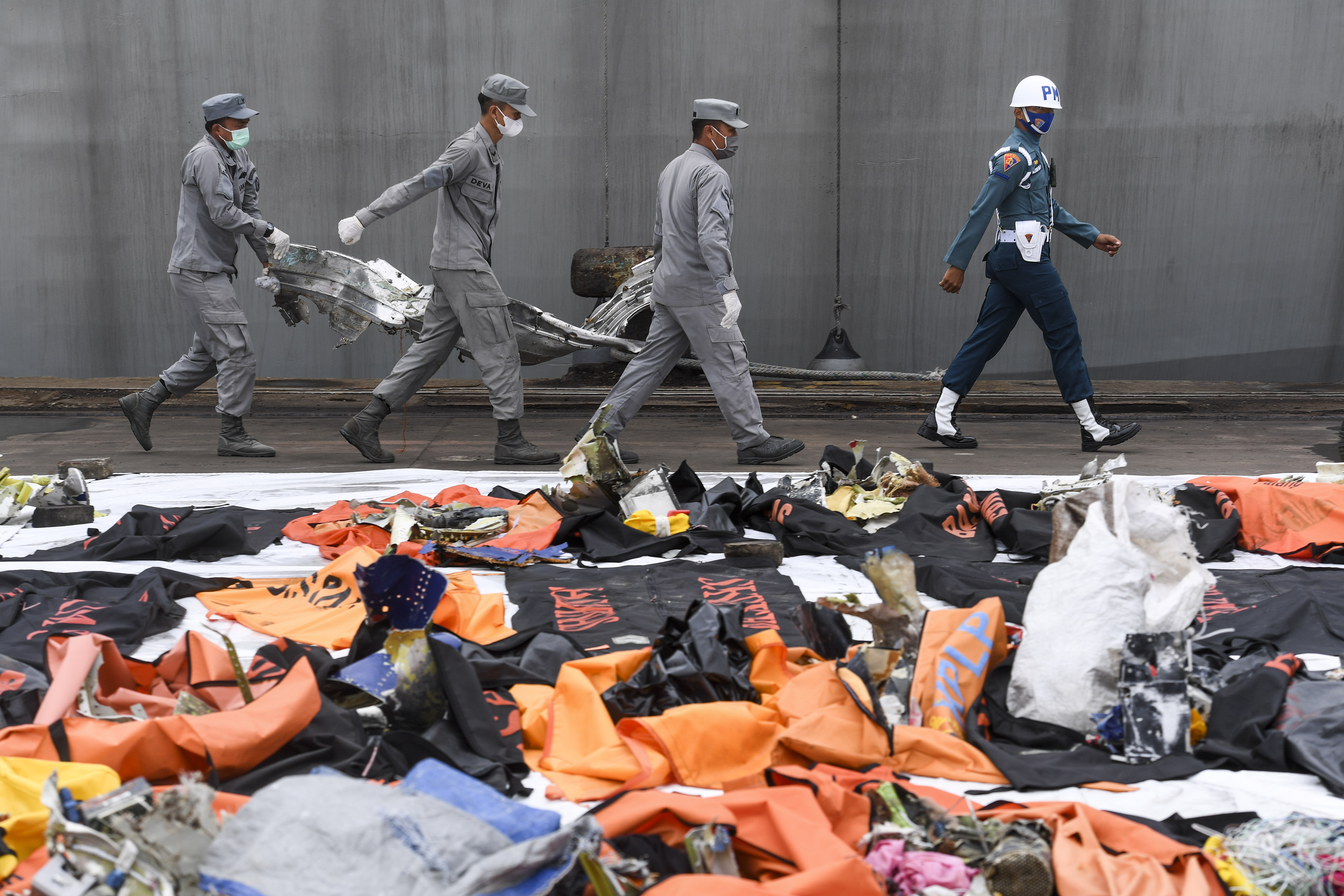 Personel Bakamla membawa temuan serpihan pesawat Sriwijaya Air PK-CLC di Dermaga JICT, Tanjung Priok, Jakarta, Senin (18/1).