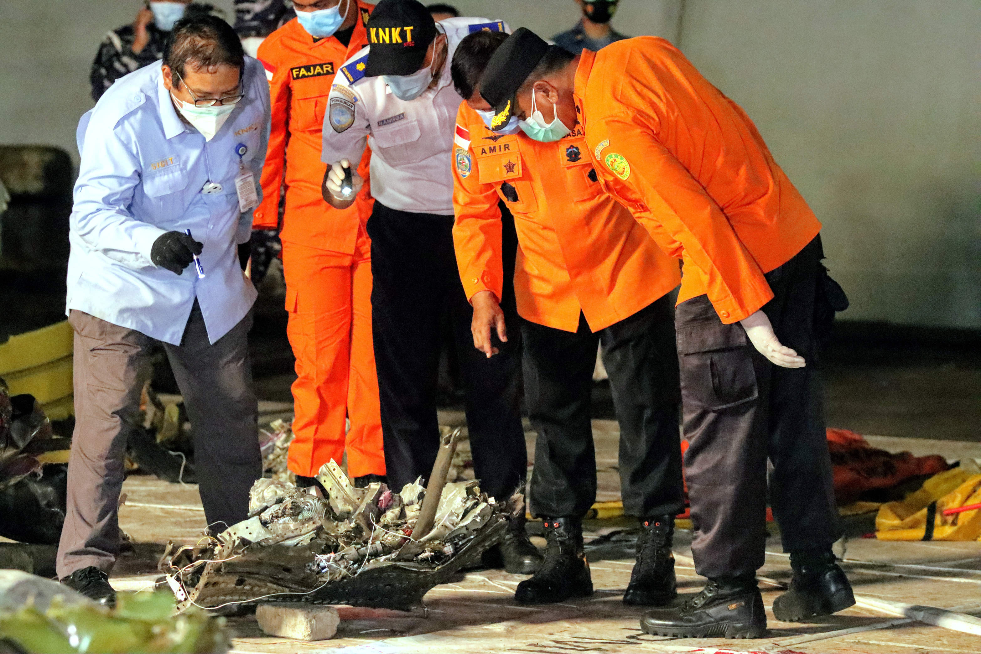 Petugas menurunkan dan memeriksa bagian pesawat dan bagian tubuh, hasil temuan pencarian dan evakuasi korban pesawat Sriwijaya Air