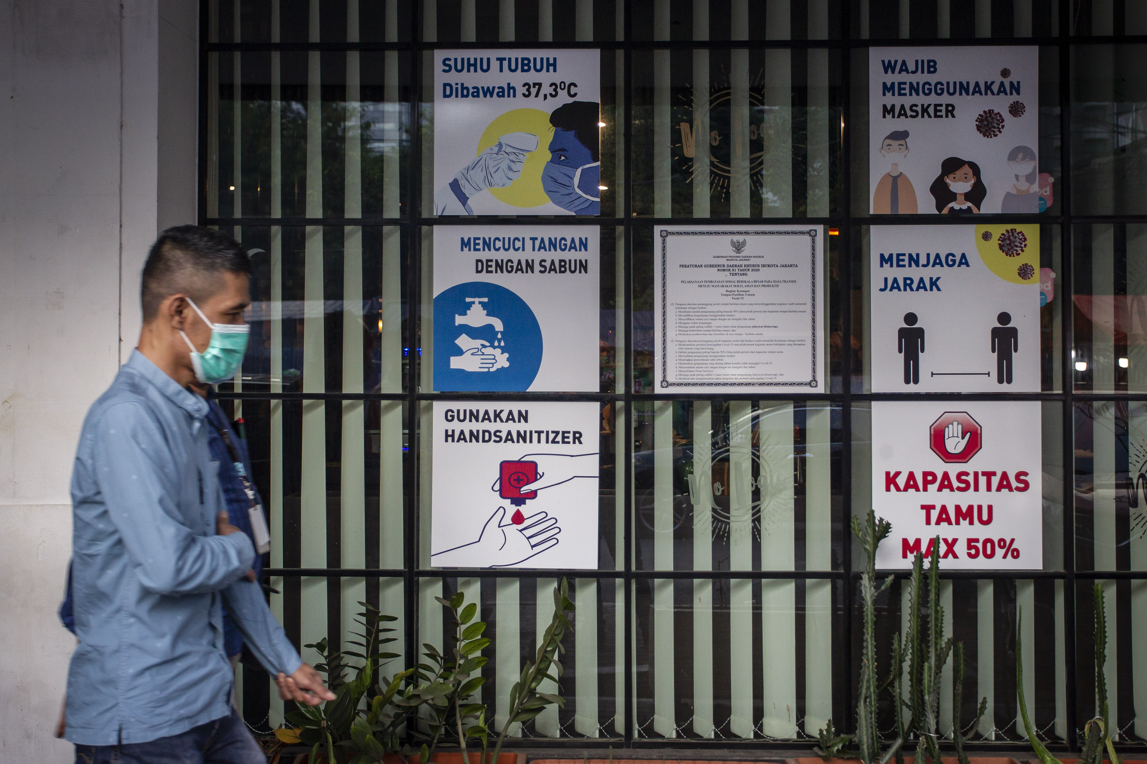 Warga melewati imbauan yang berisi terkait pencegahan penularan covid-19 di Jakarta, Jumat (8/1).