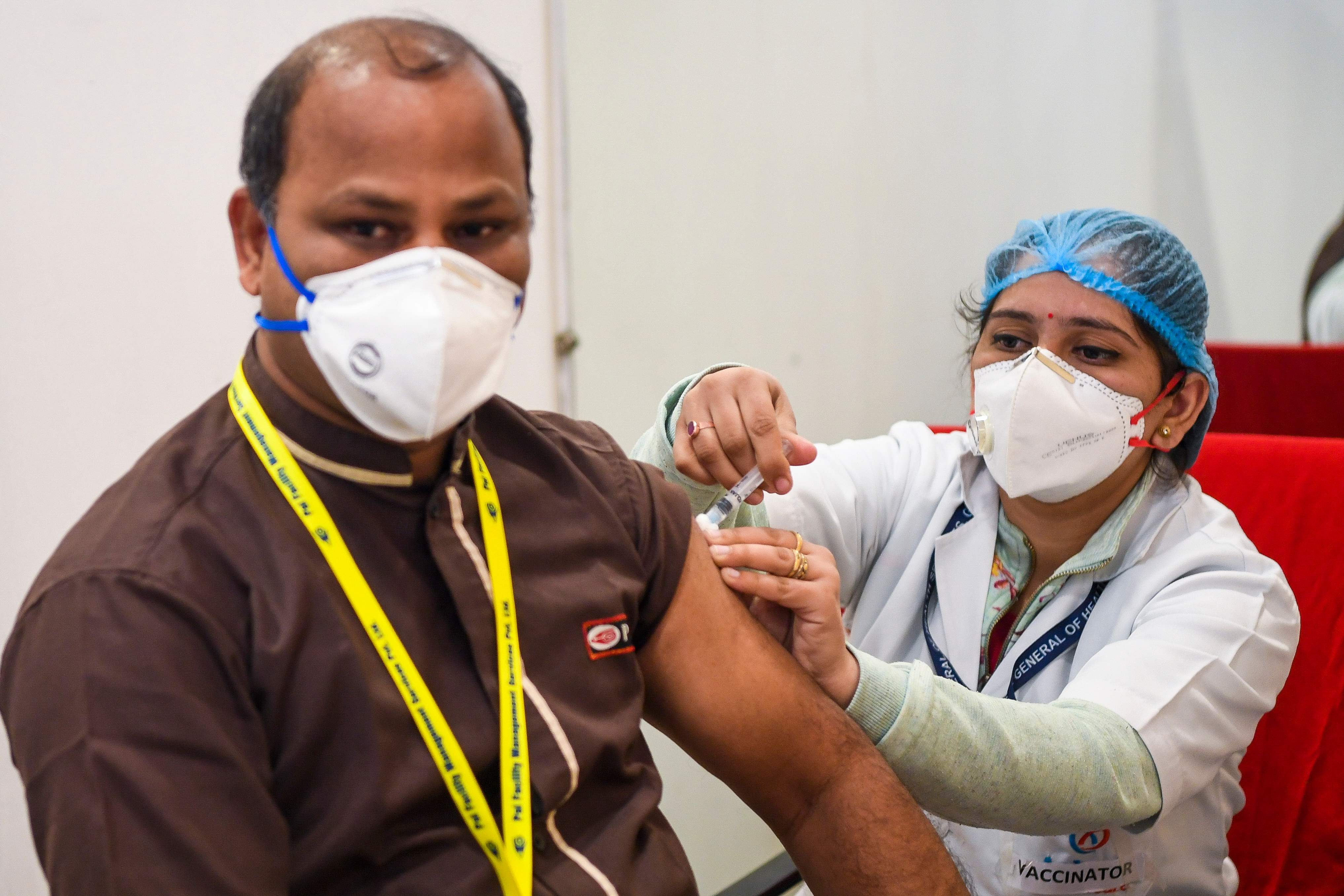 Seorang pekerja medis menyuntik seorang kolega dengan vaksin covid-19 di suatu rumah sakit di New Delhi pada Sabtu (16/1).