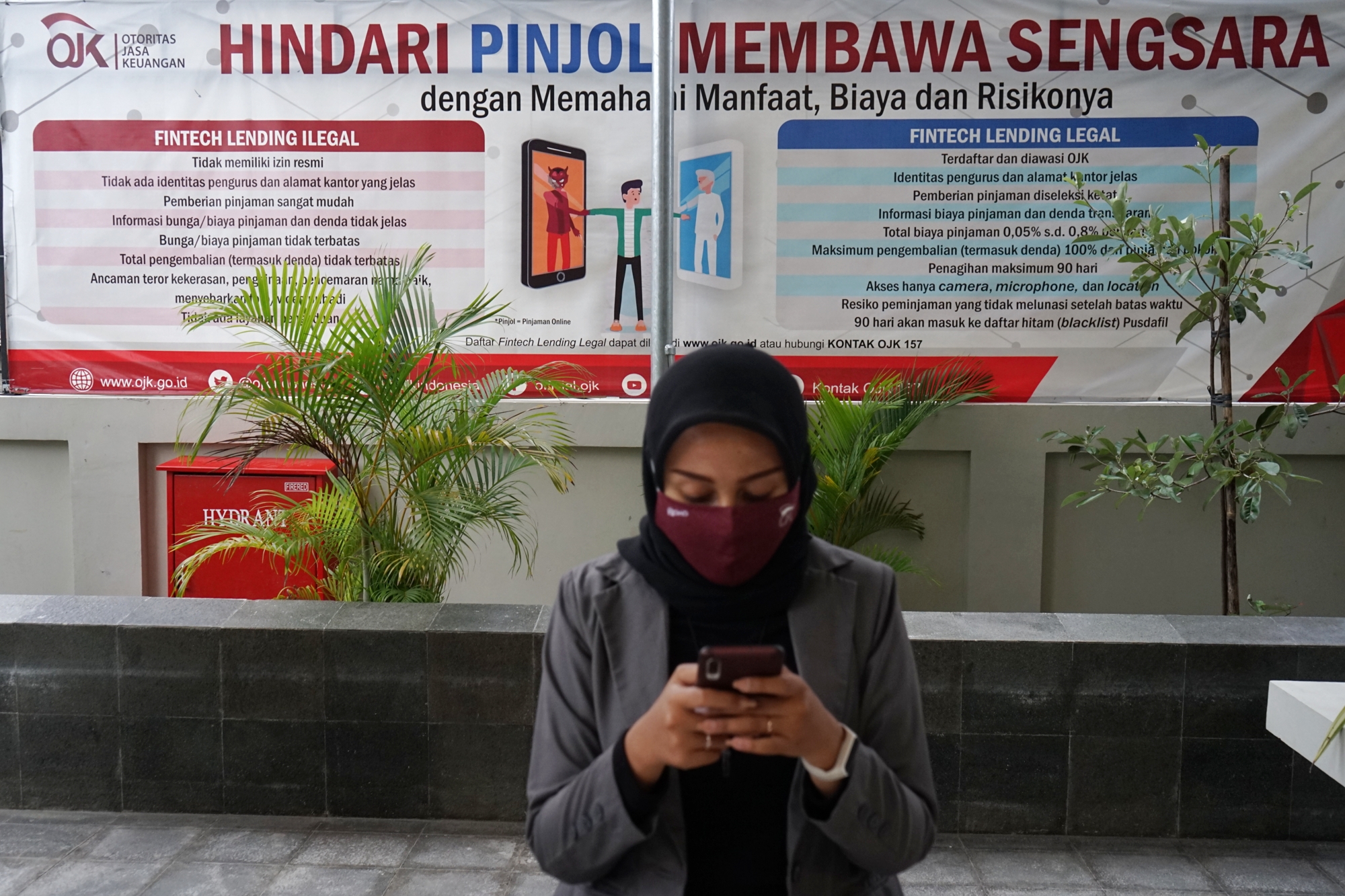 Warga berada di dekat poster edukasi waspada fintech ilegal di kantor Otoritas Jasa Keuangan (OJK) Yogyakarta, Rabu (4/11).