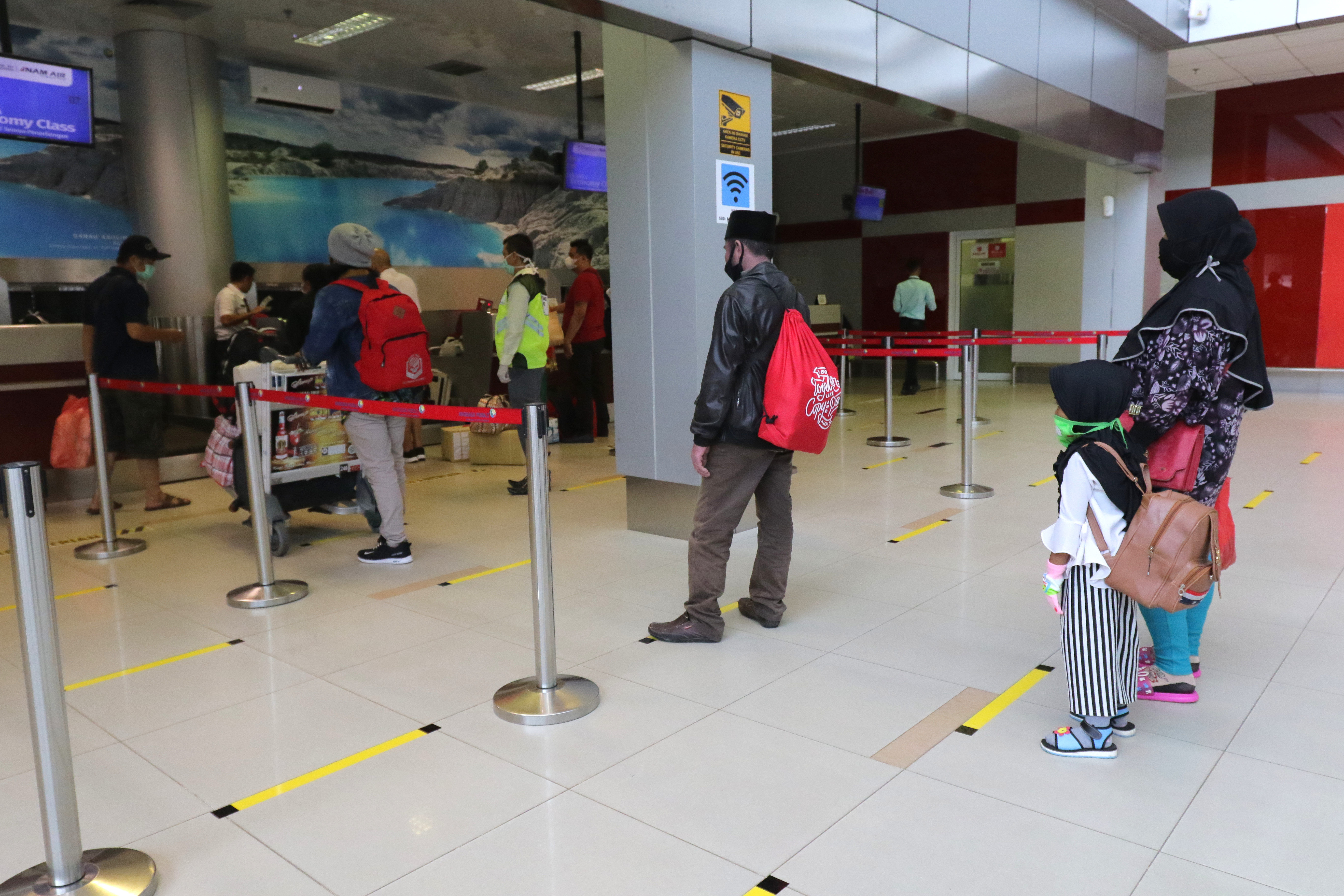 Penumpang mengantre di tempat yang telah diberi stiker panduan jarak di Bandara Depati Amir, Pangkalpinang, Kepulauan Babel.