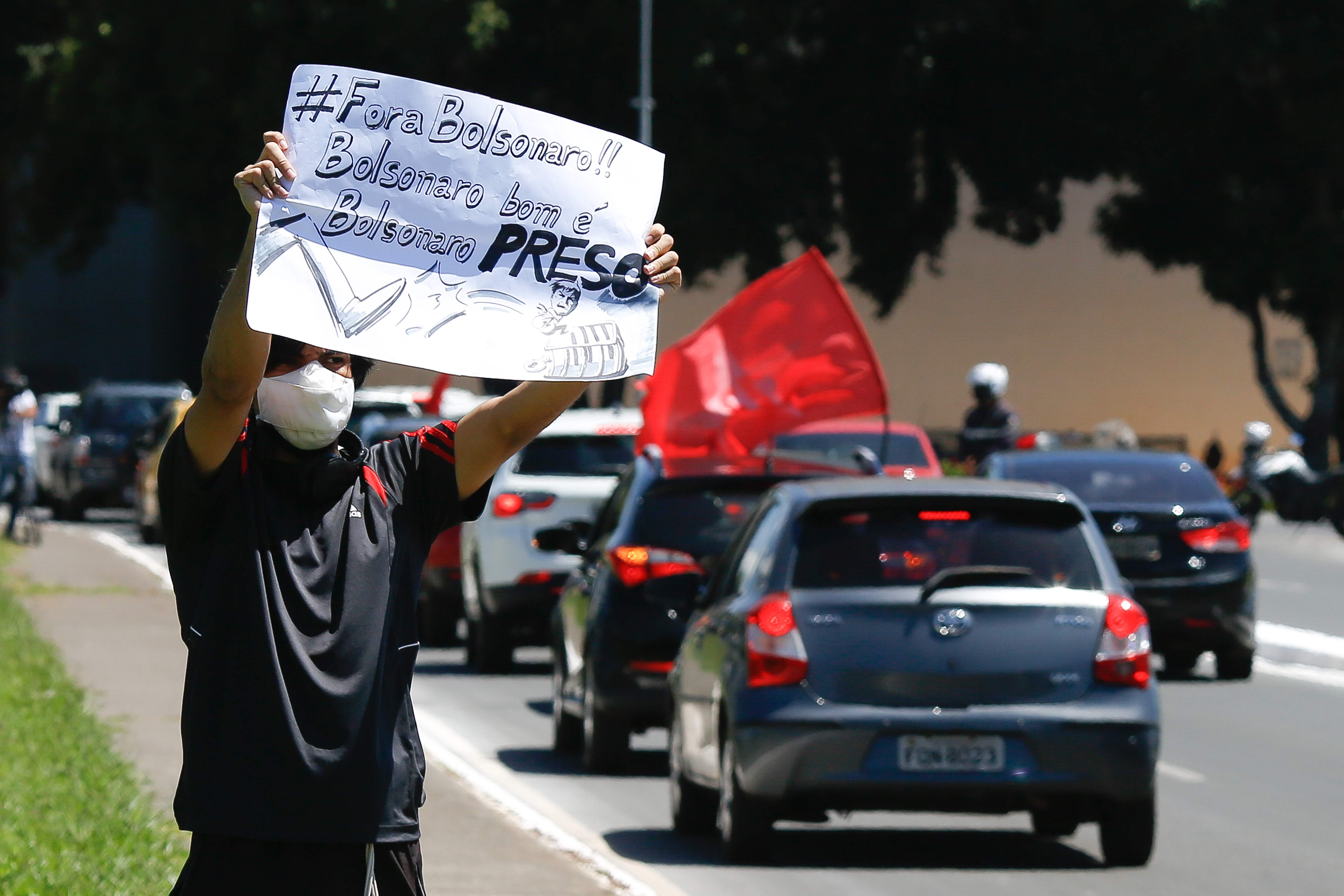 Seorang pengunjuk rasa memegang spanduk anti-Presiden Brasil Jair Bolsonaro di Brasilia, Brasil.