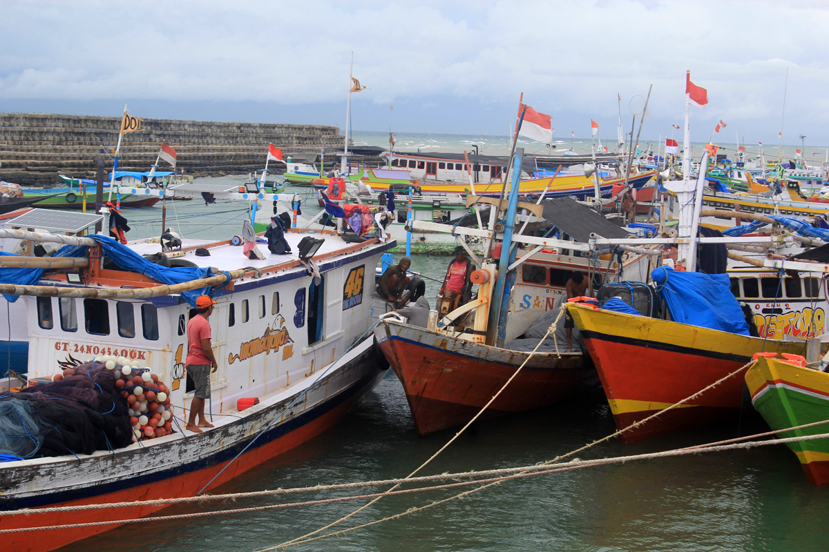 Nelayan yang tidak bisa melaut akibat gelombang tinggi menambatkan perahu di tempat pelelangan ikan di Fatubesi, Kupang, NTT, Kamis (28/1). 