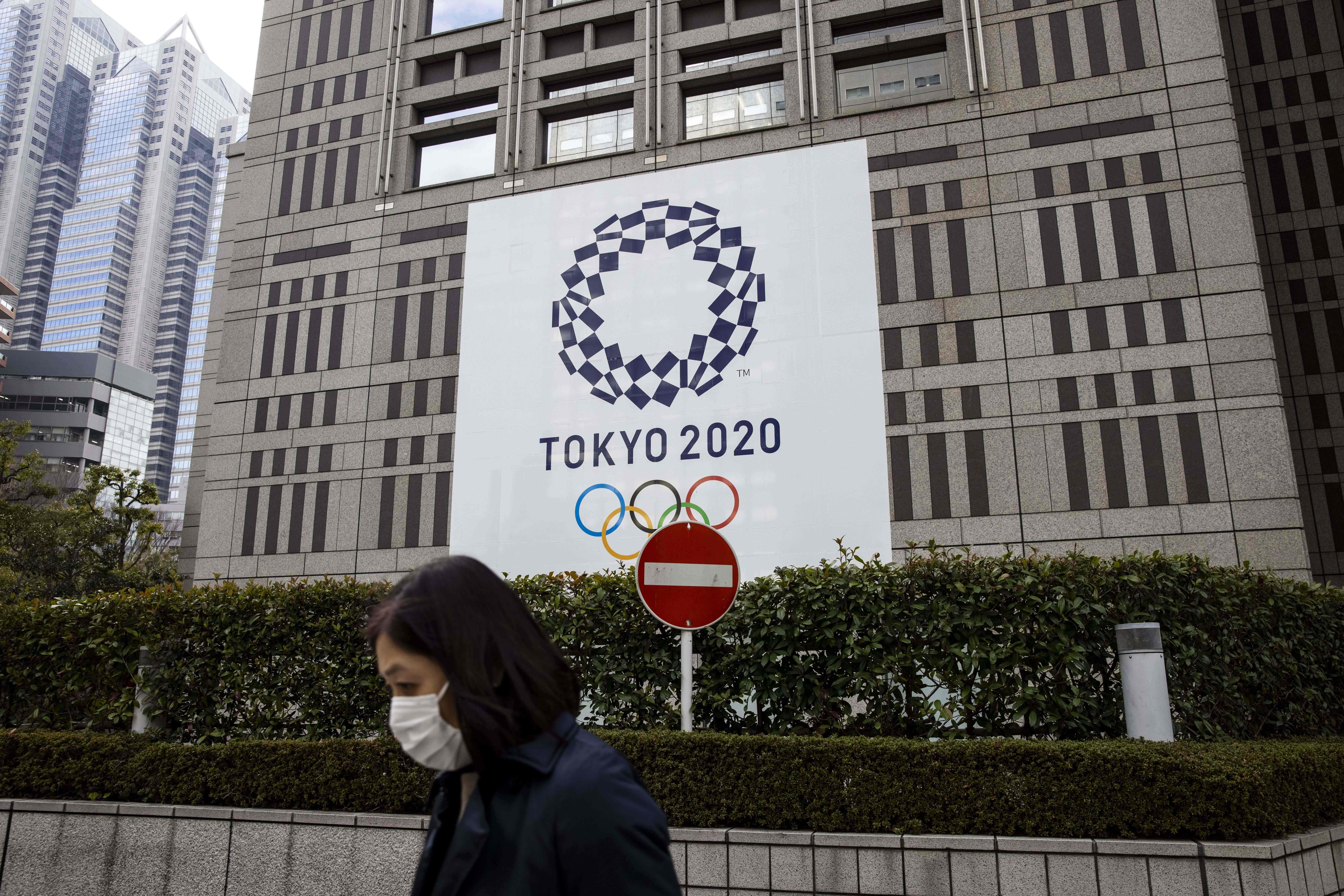 Seorang perempuan melewati Gedung Pemerintah Metropolitan Tokyo yang baner Olimpiade Tokyo 2020 di Tokyo, Jepang, Jumat (22/1). 