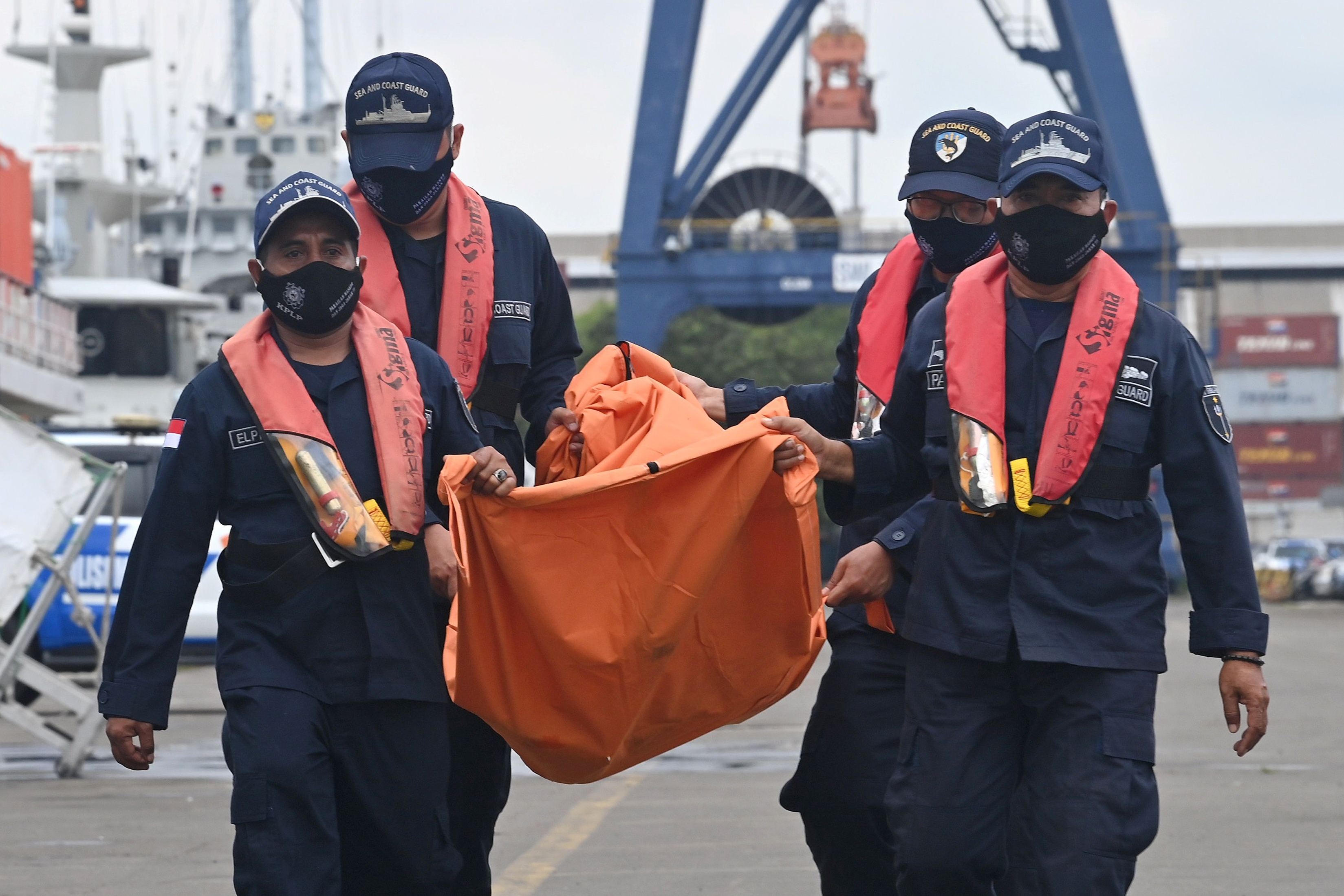 Para petugas membawa tas berisi puing-puing dari Sriwijaya Air SJ 182 di pelabuhan Tanjung Priok, Jakarta Utara, pada Rabu (13/1).
