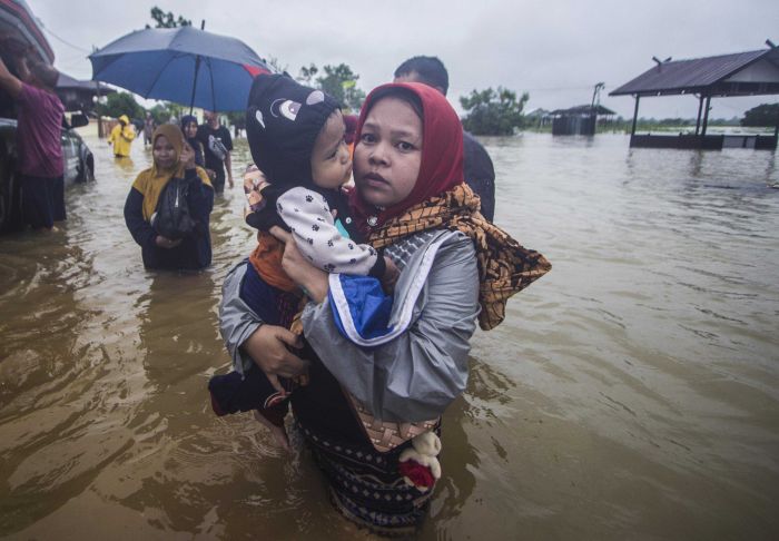 Warga menggendong anaknya melintasi banjir di Desa Kampung Melayu, Kabupaten Banjar, Kalimantan Selatan, Jumat (15/1/2021).  