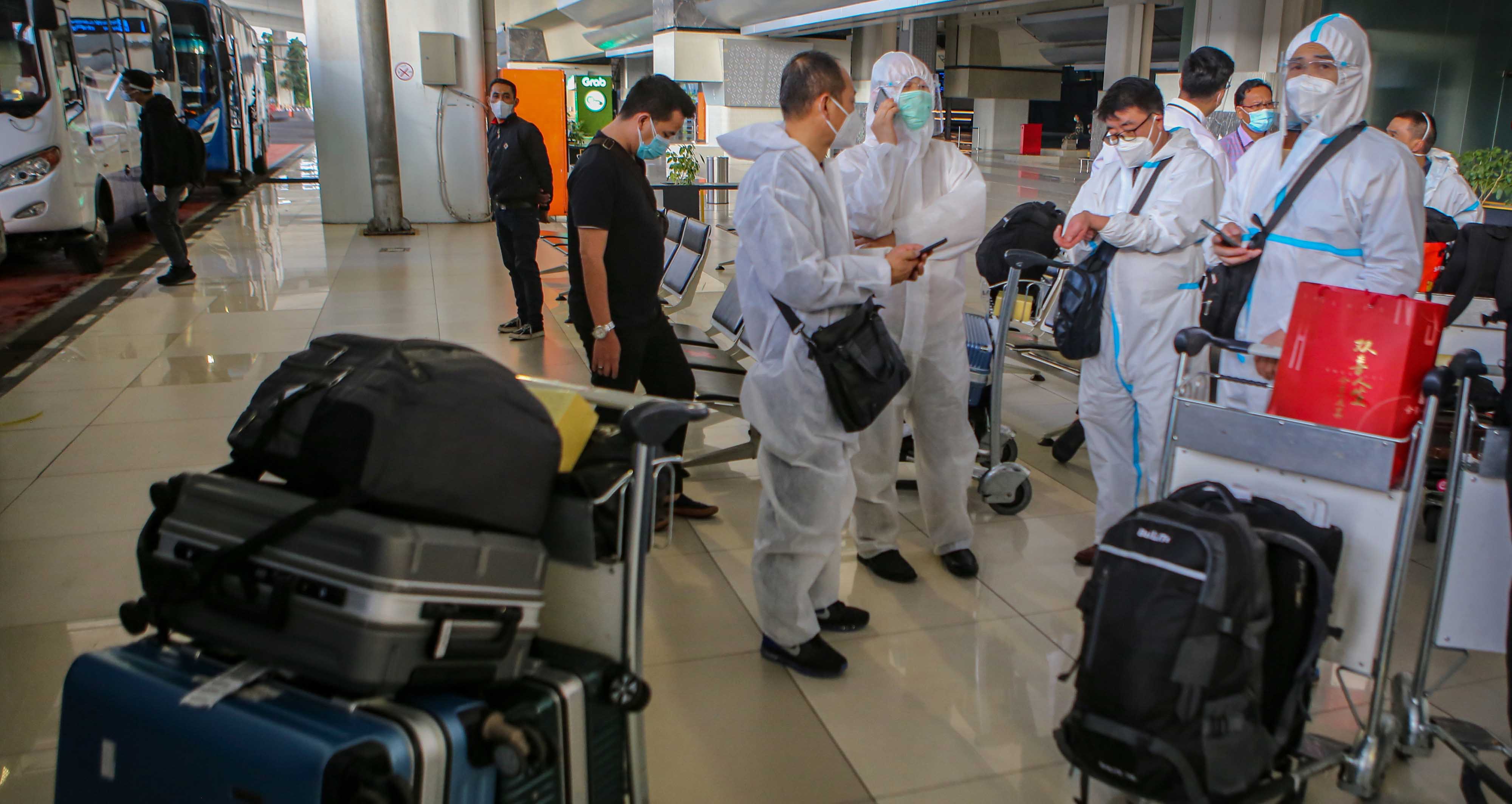  Sejumlah warga negara asing (WNA) dengan menggunakan baju hazmat tiba di Bandara Internasional Soekarno Hatta, Tangerang,  Sabtu (2/1).