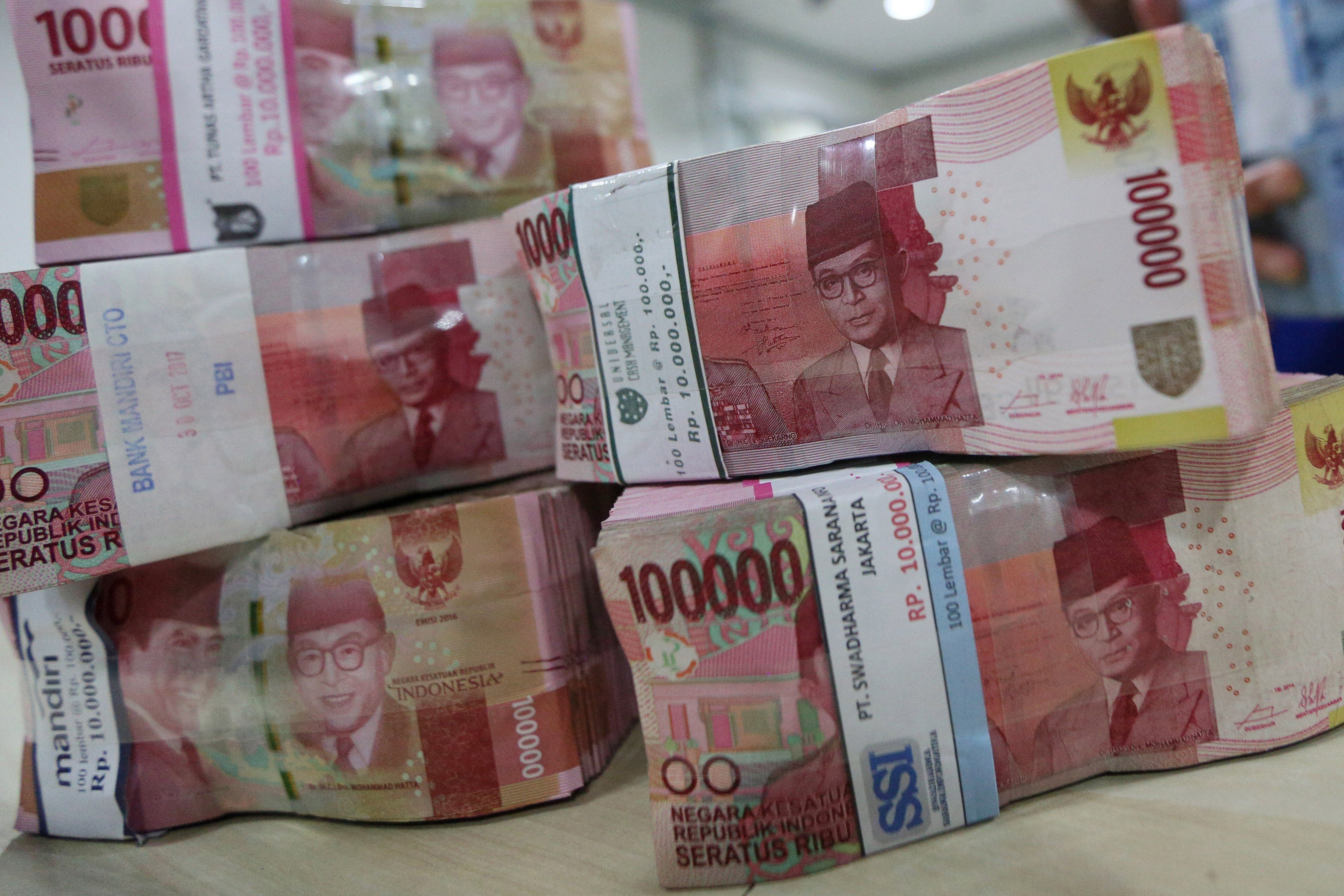Petugas menghitung tumpukan uang di Jakarta.