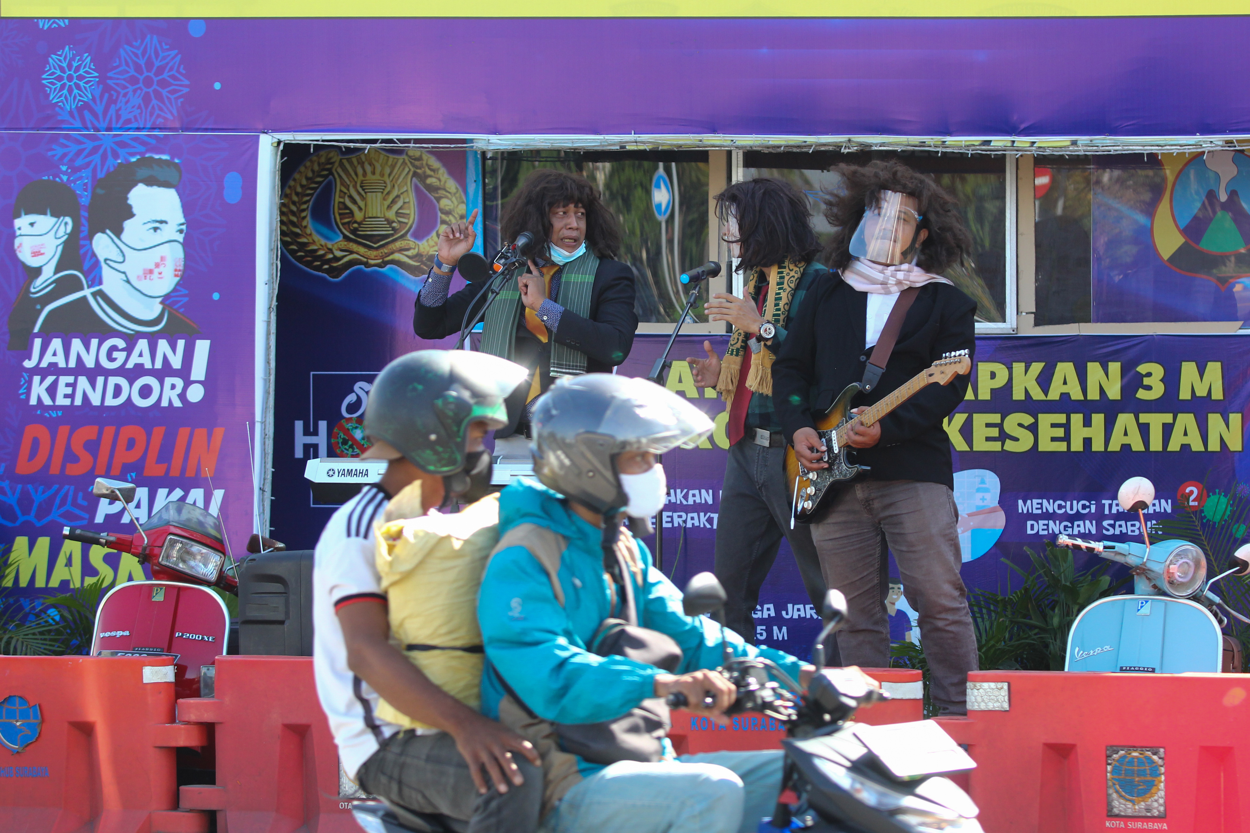 PROTOKOL KESEHATAN: Polisi berpakaian sipil bermain musik saat sosialisasi penerapan protokol kesehatan di depan pos pengamanan di Surabaya.
